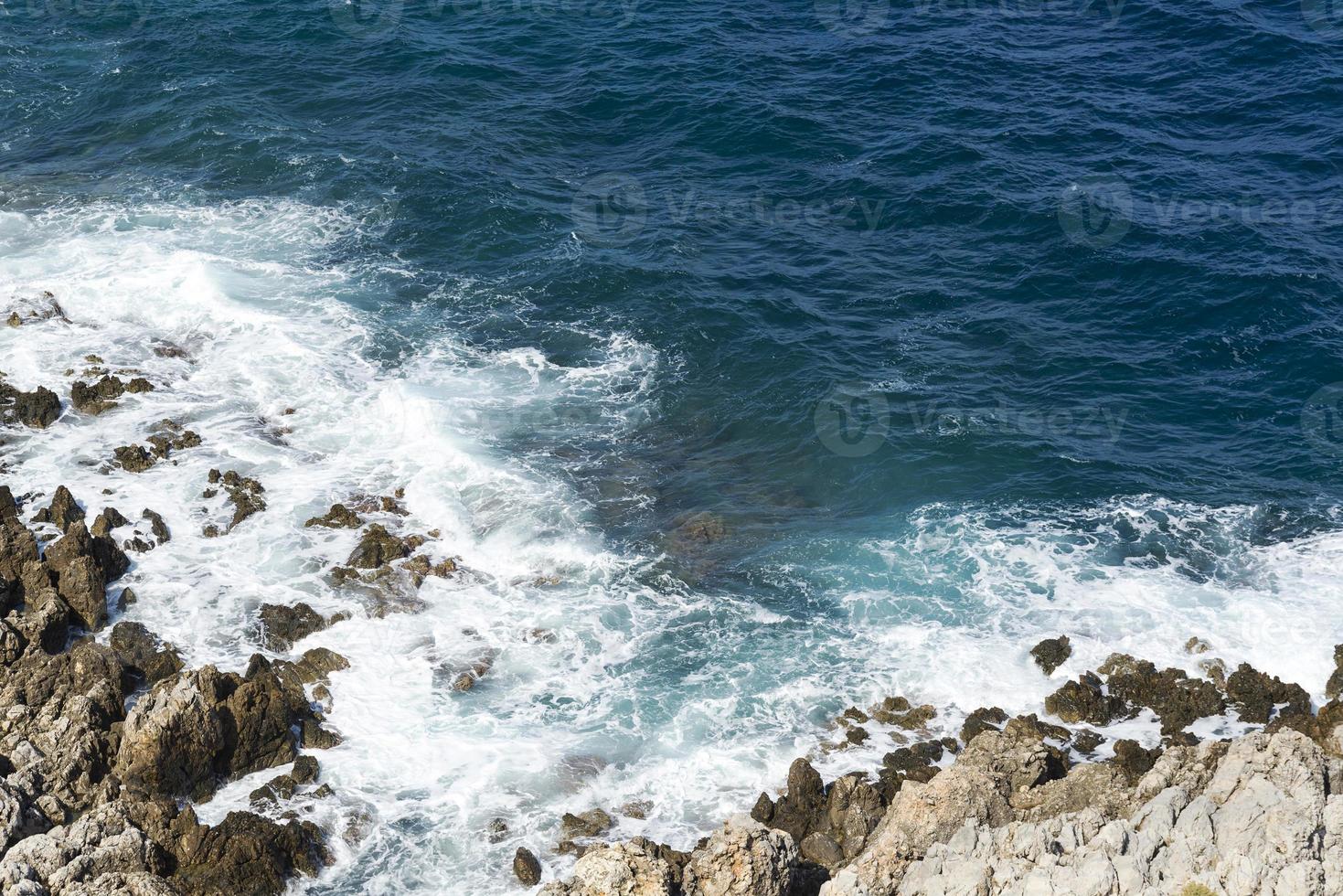 las olas rompiendo en una playa pedregosa, formando un rocío. olas y salpicaduras en la playa. olas rompiendo contra las rocas. foto