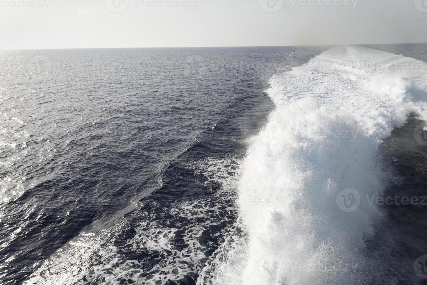 Trail on water surface behind of fast moving motor boat photo