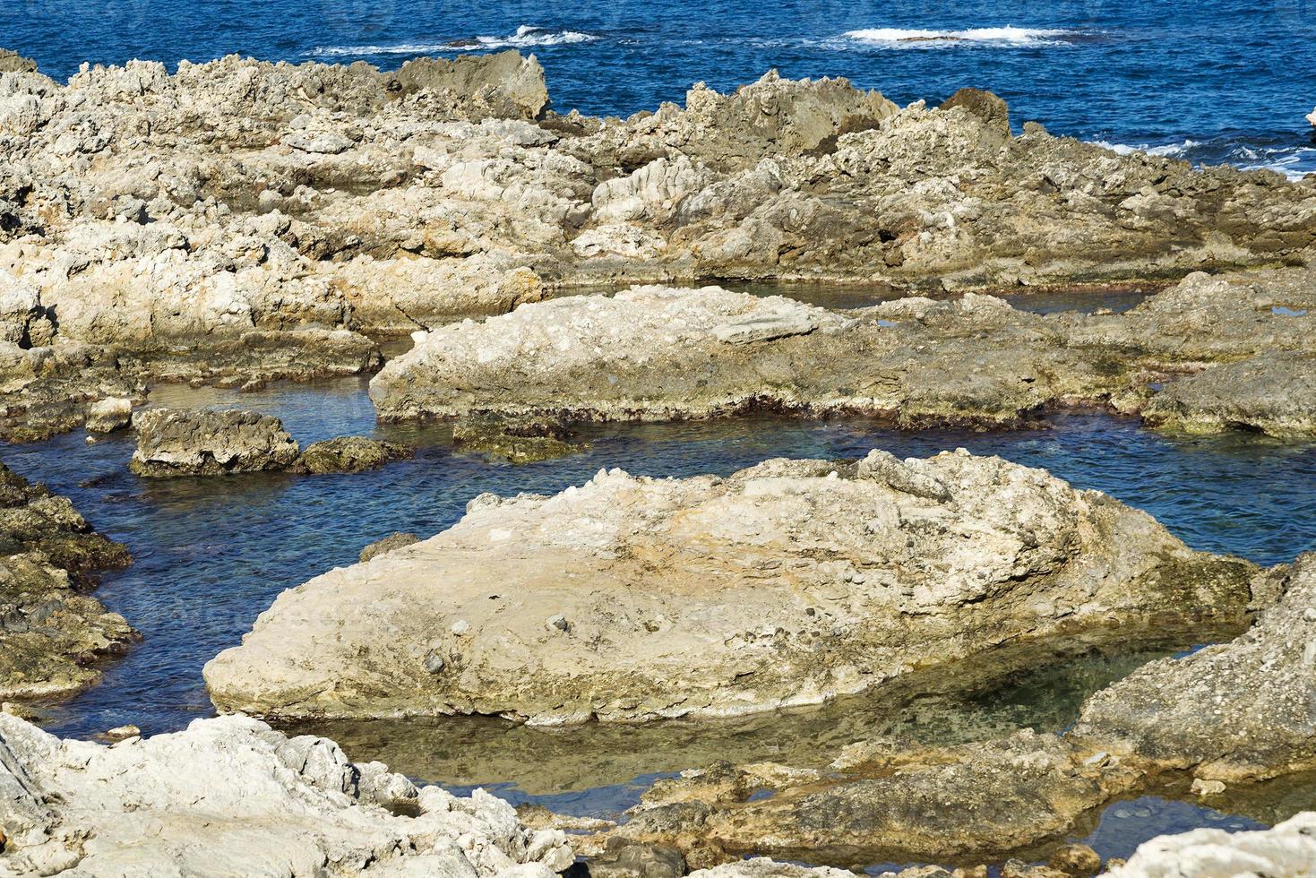 las olas rompiendo en una playa pedregosa, formando un rocío. olas y salpicaduras en la playa. olas rompiendo contra las rocas. foto