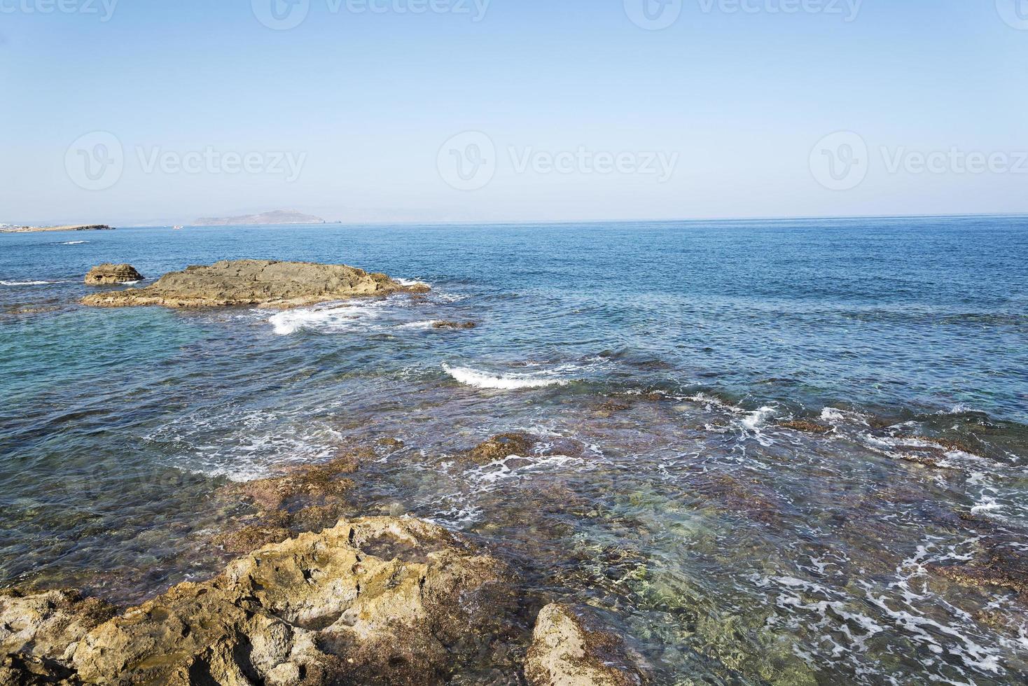 The waves breaking on a stony beach, forming a spray. Wave and splashes on beach. Waves crashing onto rocks. photo