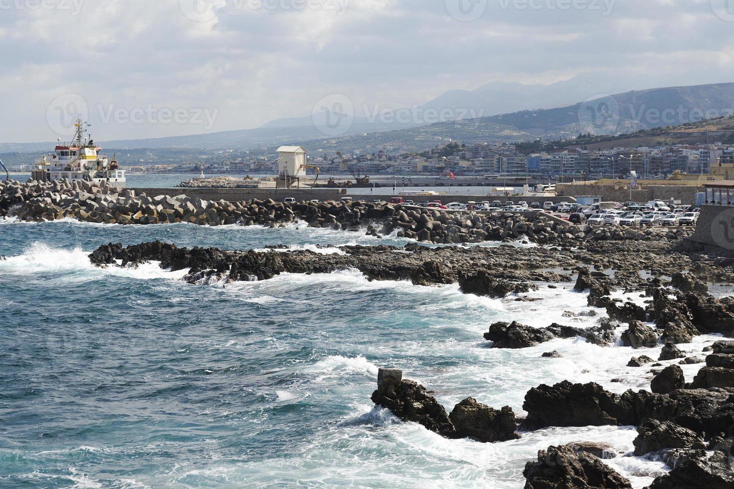The waves breaking on a stony beach, forming a spray. Wave and splashes on beach. Waves crashing onto rocks. photo