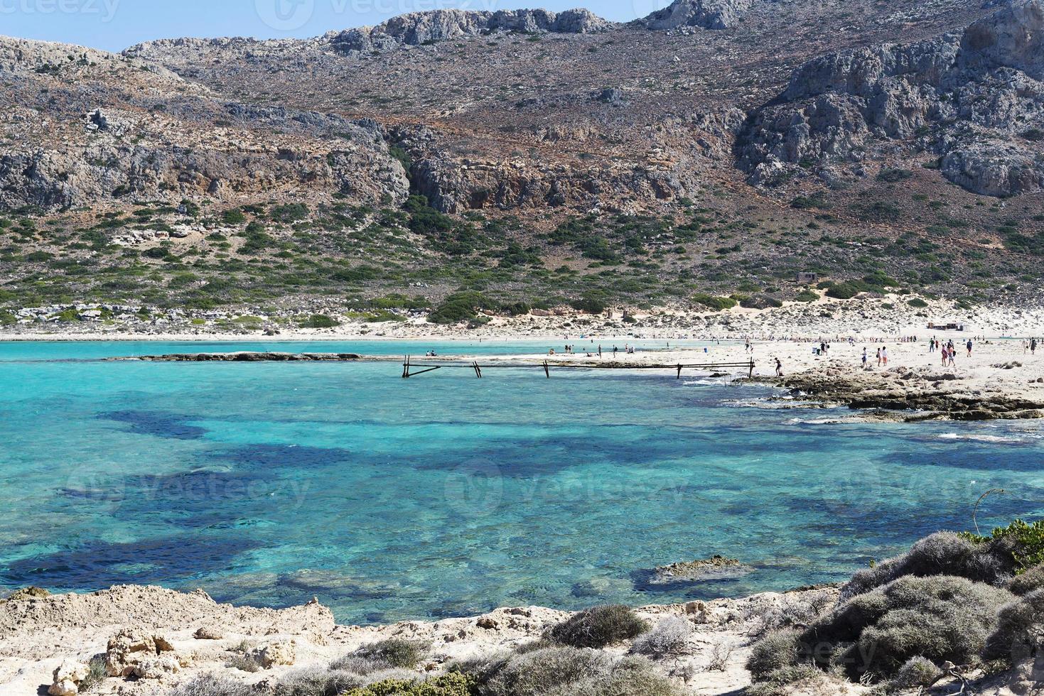 paisaje marino con un barco entretenido en el horizonte y un muelle de piedra en primer plano foto