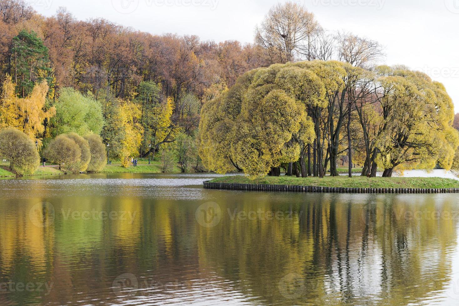 día de otoño en el parque con reflejo de árboles en el agua. foto