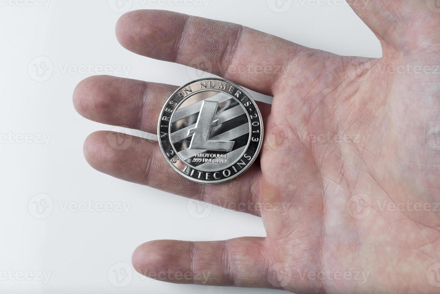 Hand holds one Litecoin on a white background. photo