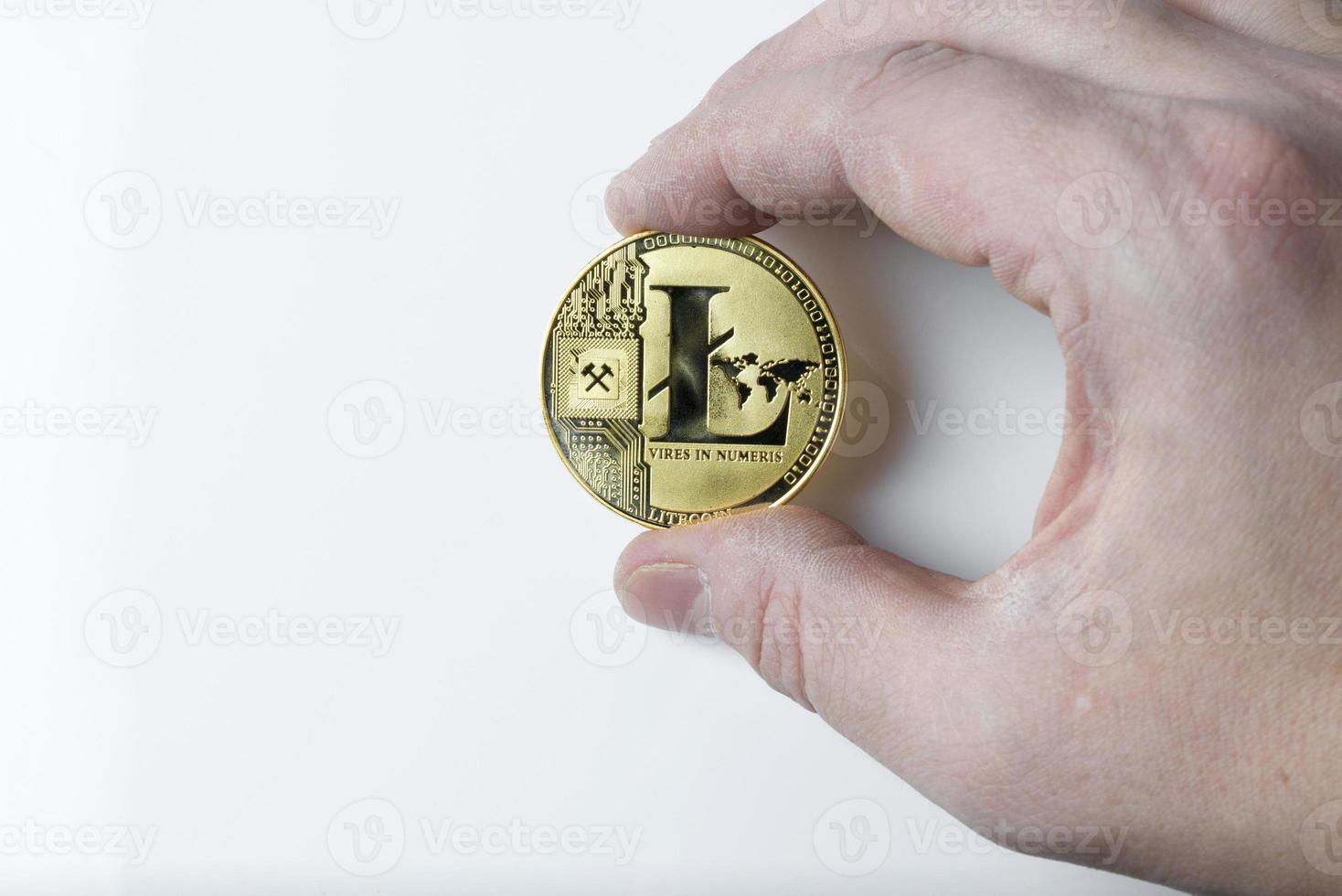 Hand holds one Litecoin on a white background. photo