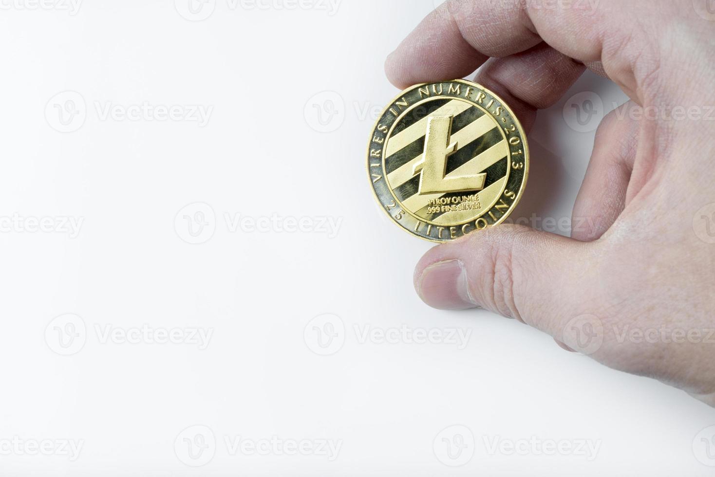 Hand holds one Litecoin on a white background. photo