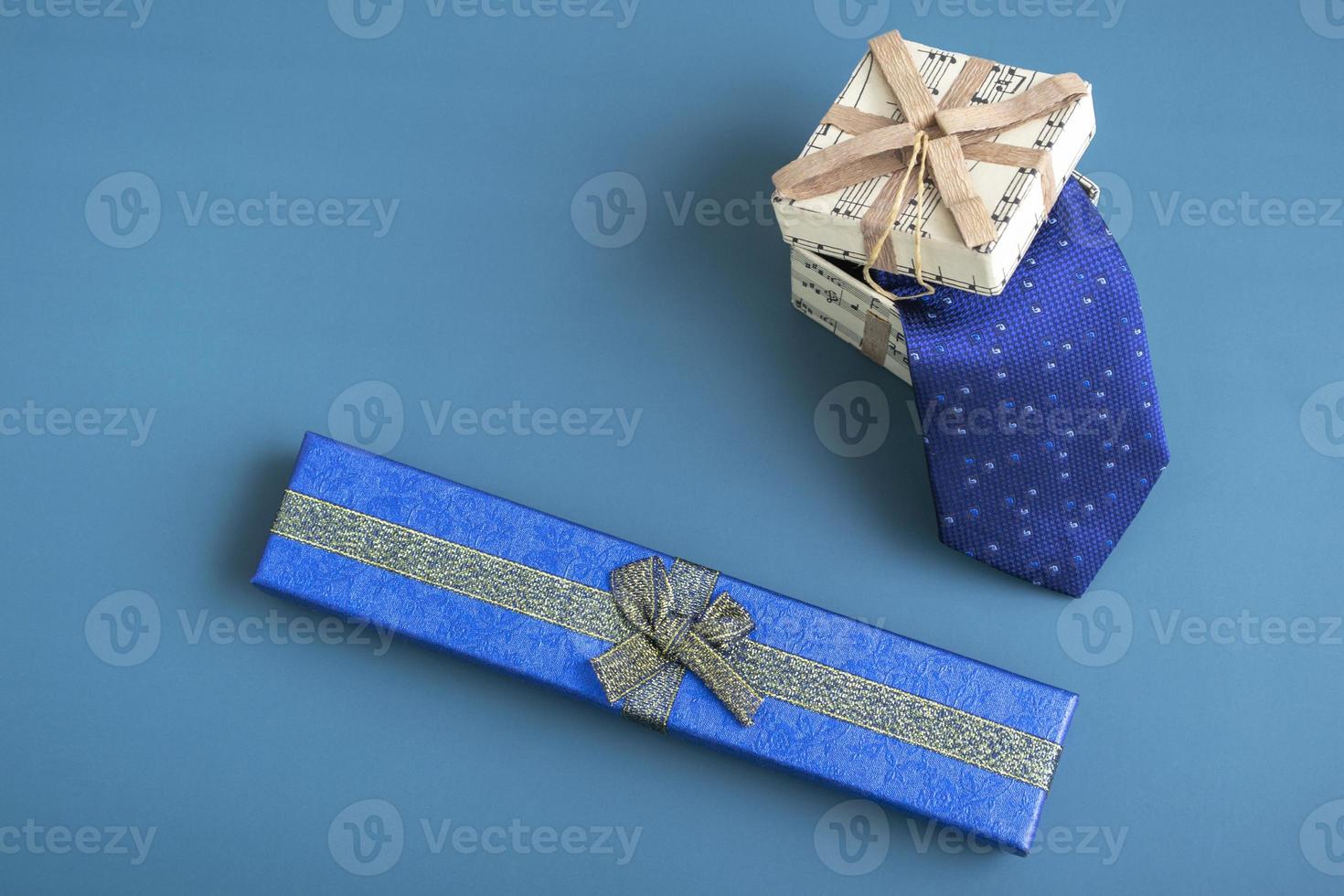 Gift box with a tie on a turquoise background. Holiday gifts closeup