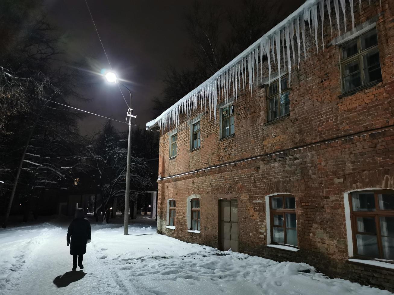 winter evening icicles hanging from the roof in the light of a lantern photo