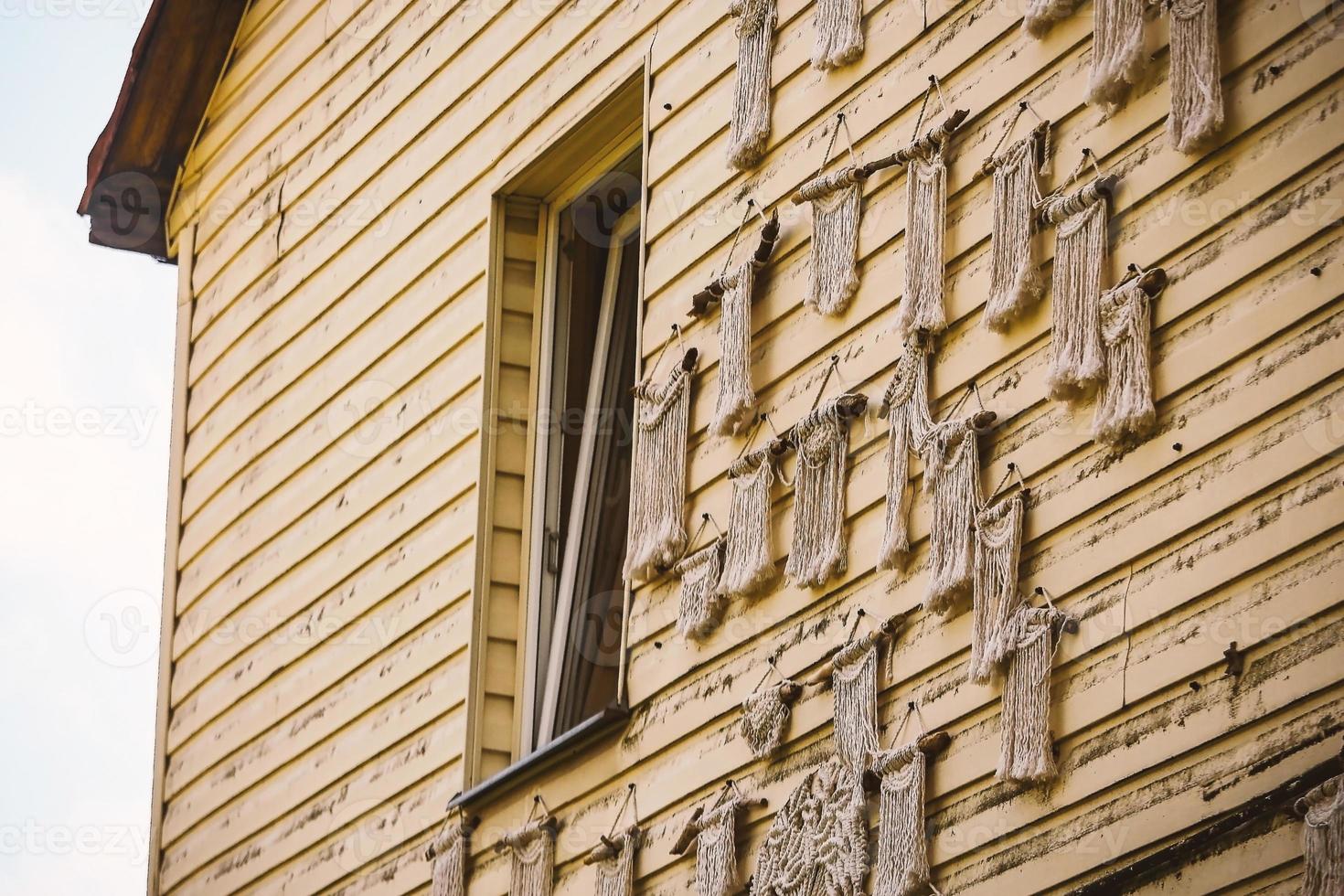 Yellow plank building wall with window and macrame weaved decorations photo