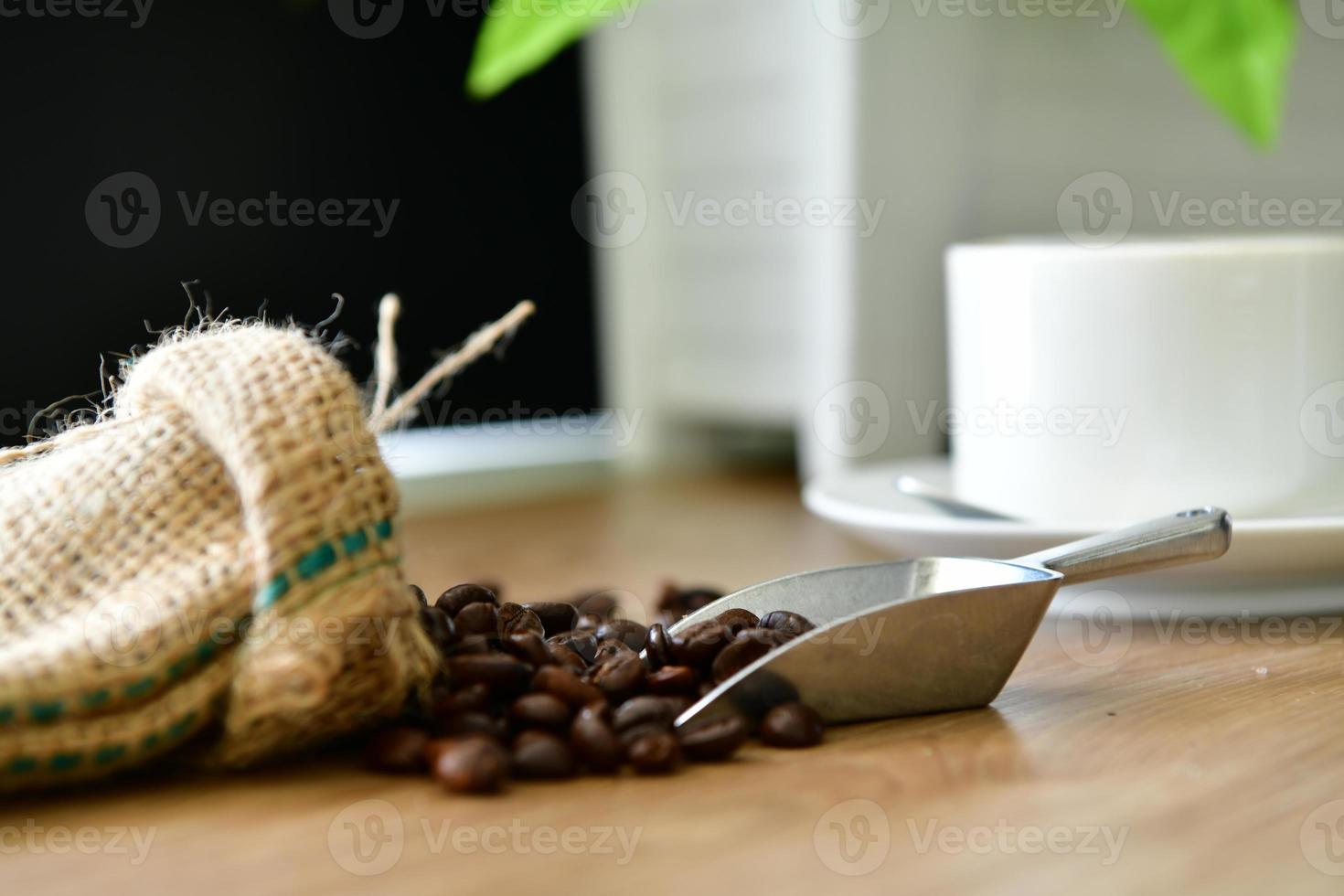 Morning hot coffee for those who love to drink coffee And roasted coffee beans in a sack poured on a wooden floor for grinding and brew to drink freshly. photo