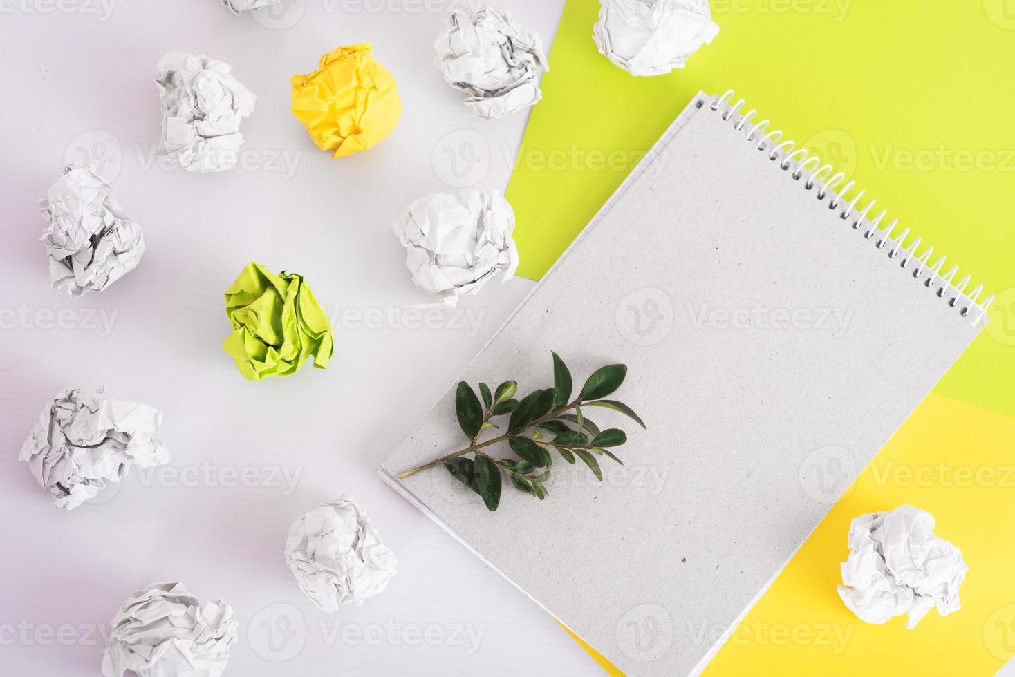 organic paper notebook with green twig among crumpled paper and colored paper on white background. zero waste concept photo