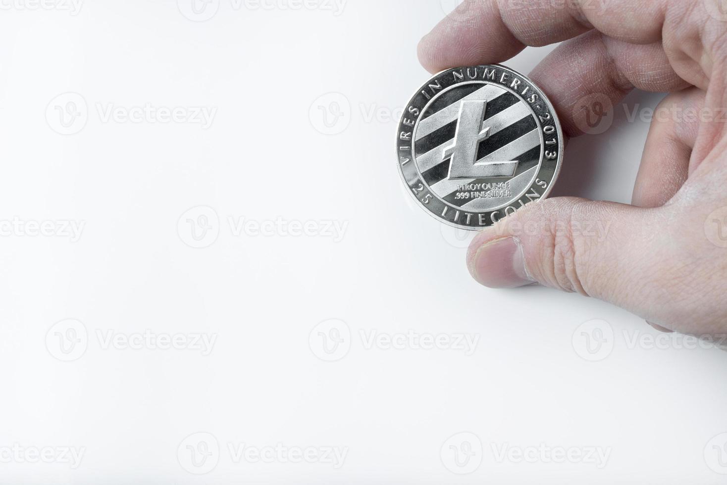 Hand holds one Litecoin on a white background. photo