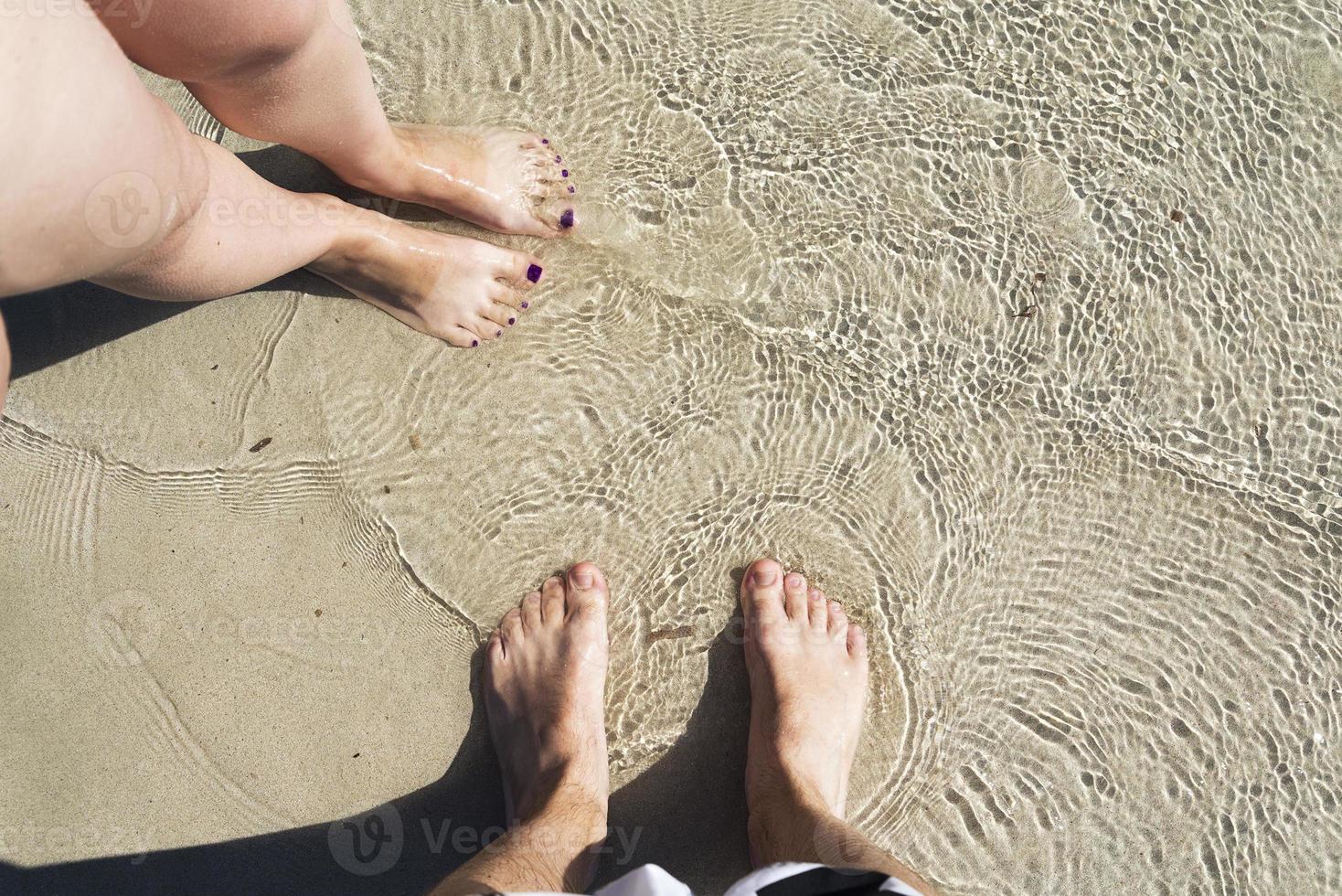 Two pairs on the sand with sea water. photo