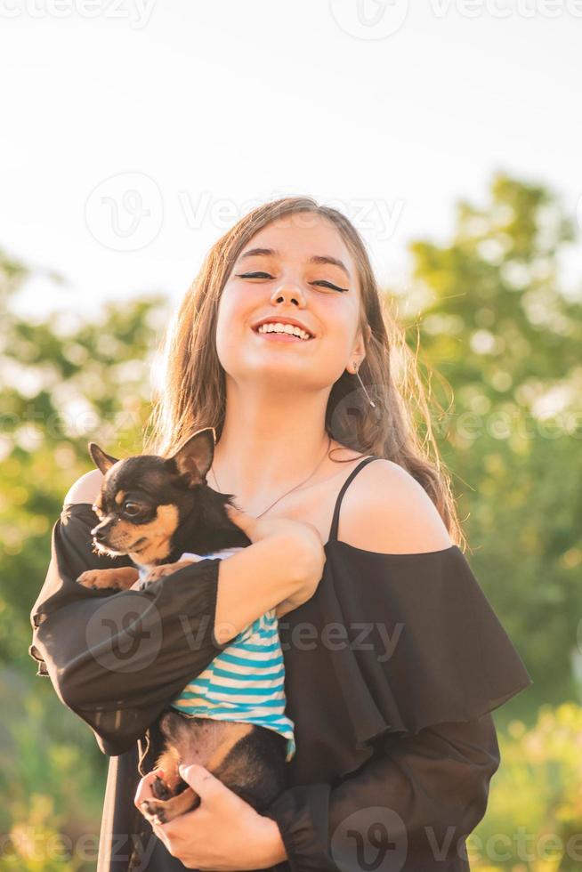 chica morena adolescente con un perro. la niña se regocija abrazando a chihuahua. foto