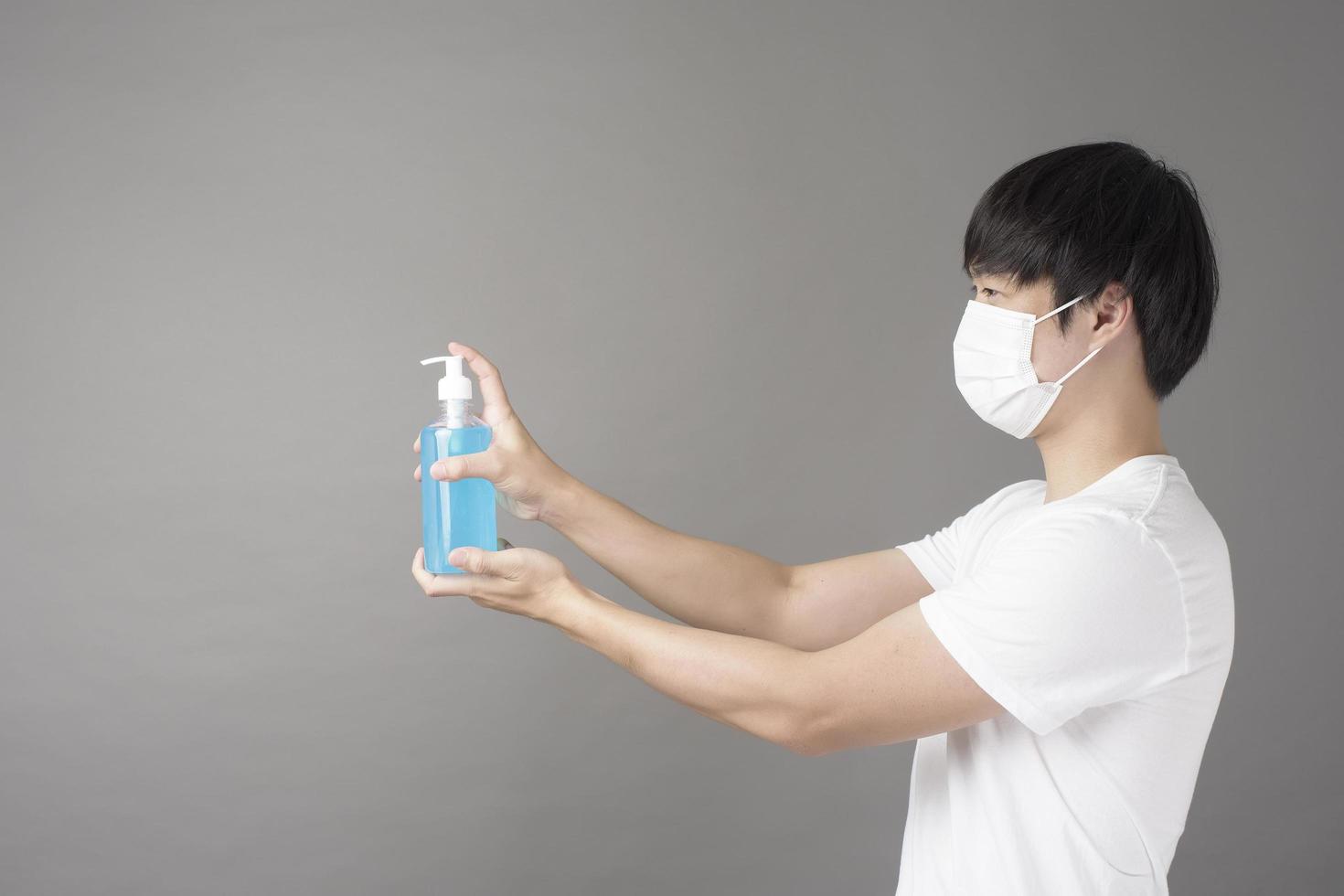 A handsome man with surgical mask is using alcohol hand sanitizer photo