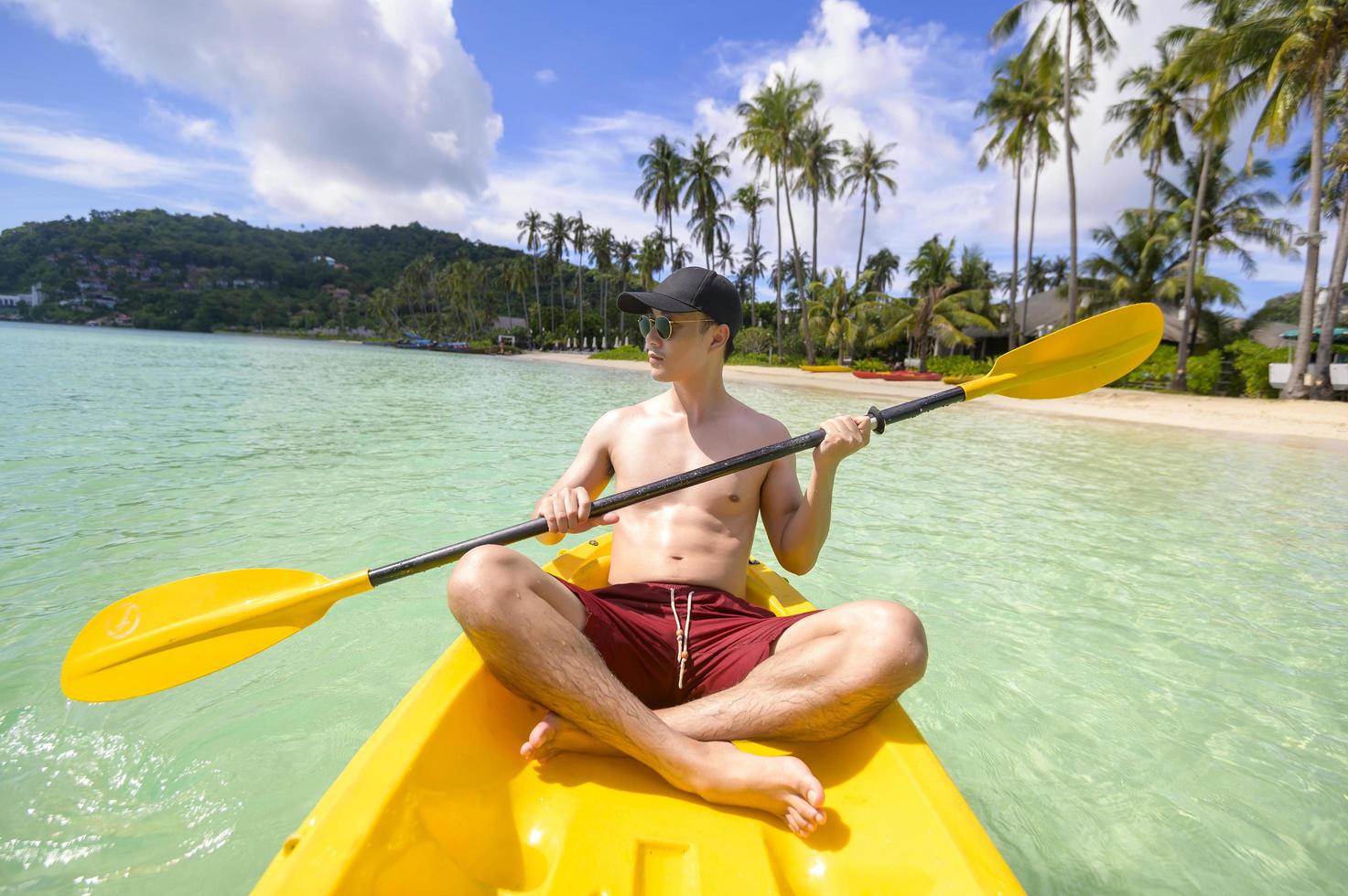 un joven deportista haciendo kayak en el océano en un día soleado foto