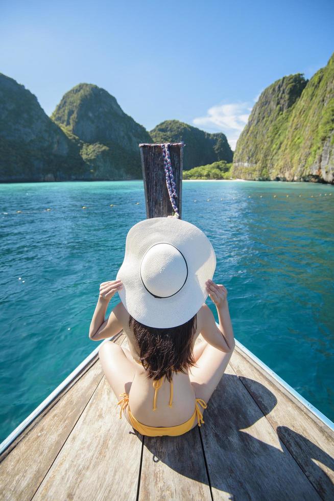 View of woman in swimsuit enjoying on thai traditional longtail Boat over beautiful mountain and ocean, Phi phi Islands, Thailand photo