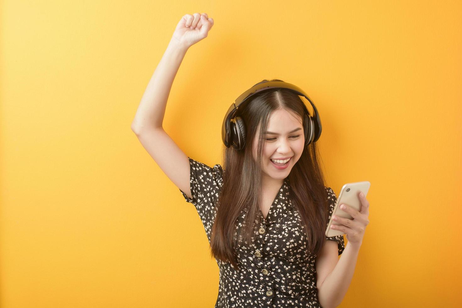 Music lover woman is enjoying with headset on yellow background photo