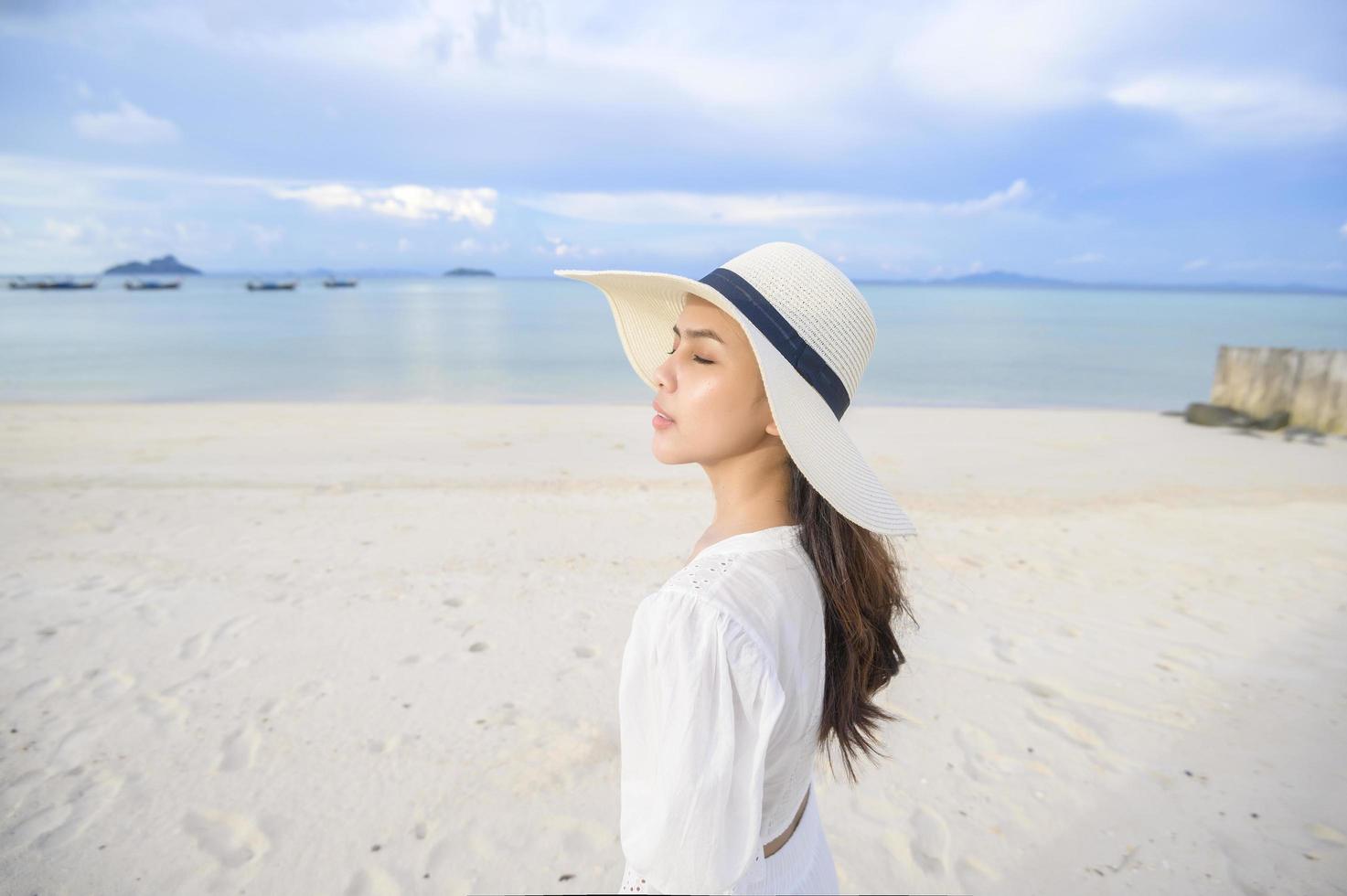 una hermosa mujer feliz con vestido blanco disfrutando y relajándose en el concepto de playa, verano y vacaciones foto