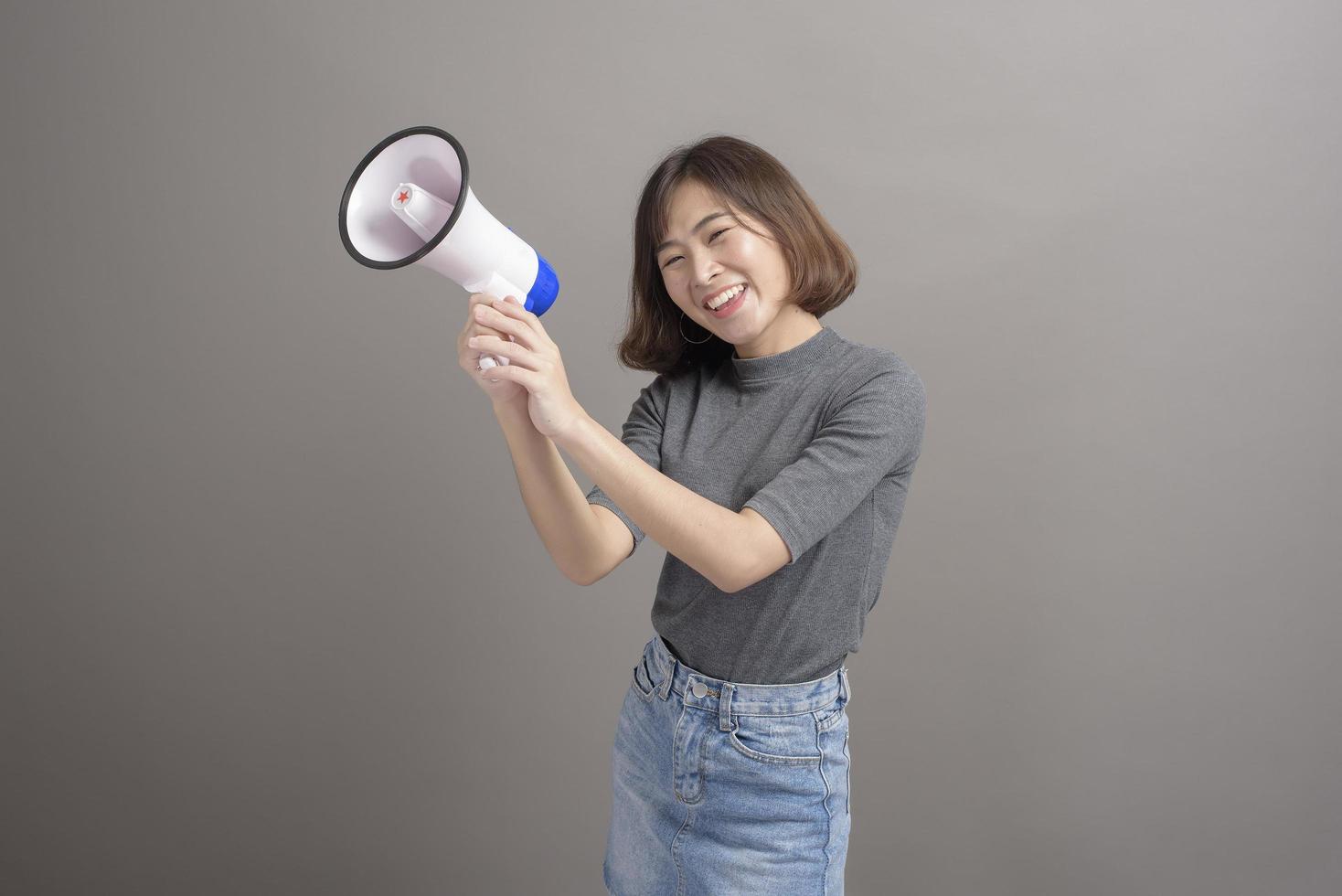 retrato de una joven y hermosa mujer asiática sosteniendo un megáfono sobre el fondo del estudio. foto