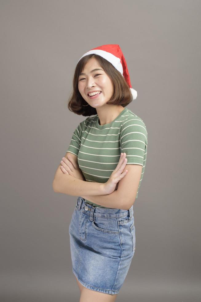 retrato de una mujer hermosa con sombrero rojo de santa claus sosteniendo una caja de regalo sobre fondo de estudio, concepto de navidad y año nuevo foto