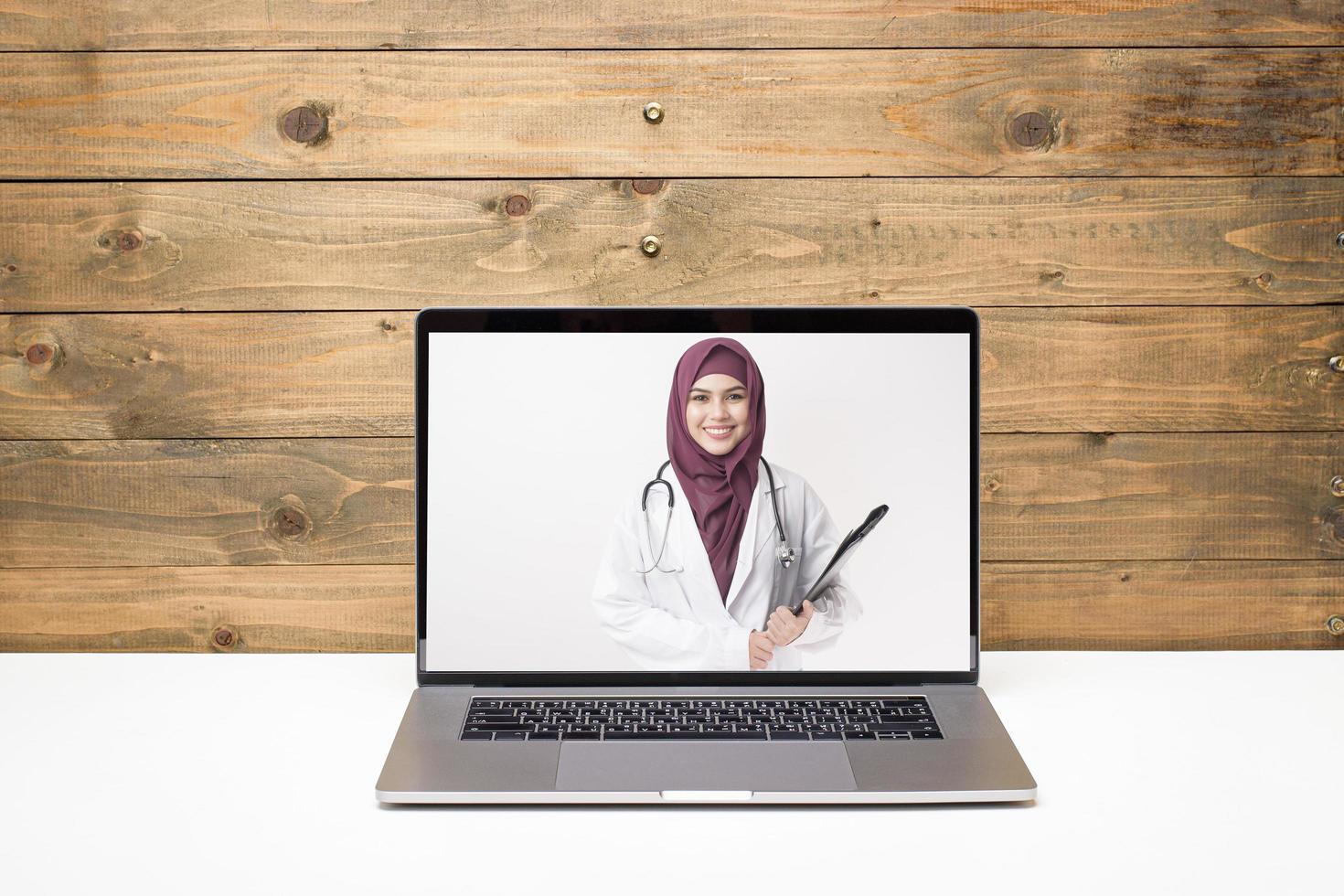 Female Muslim doctor making video call on social network with patient consulting about health problems. photo