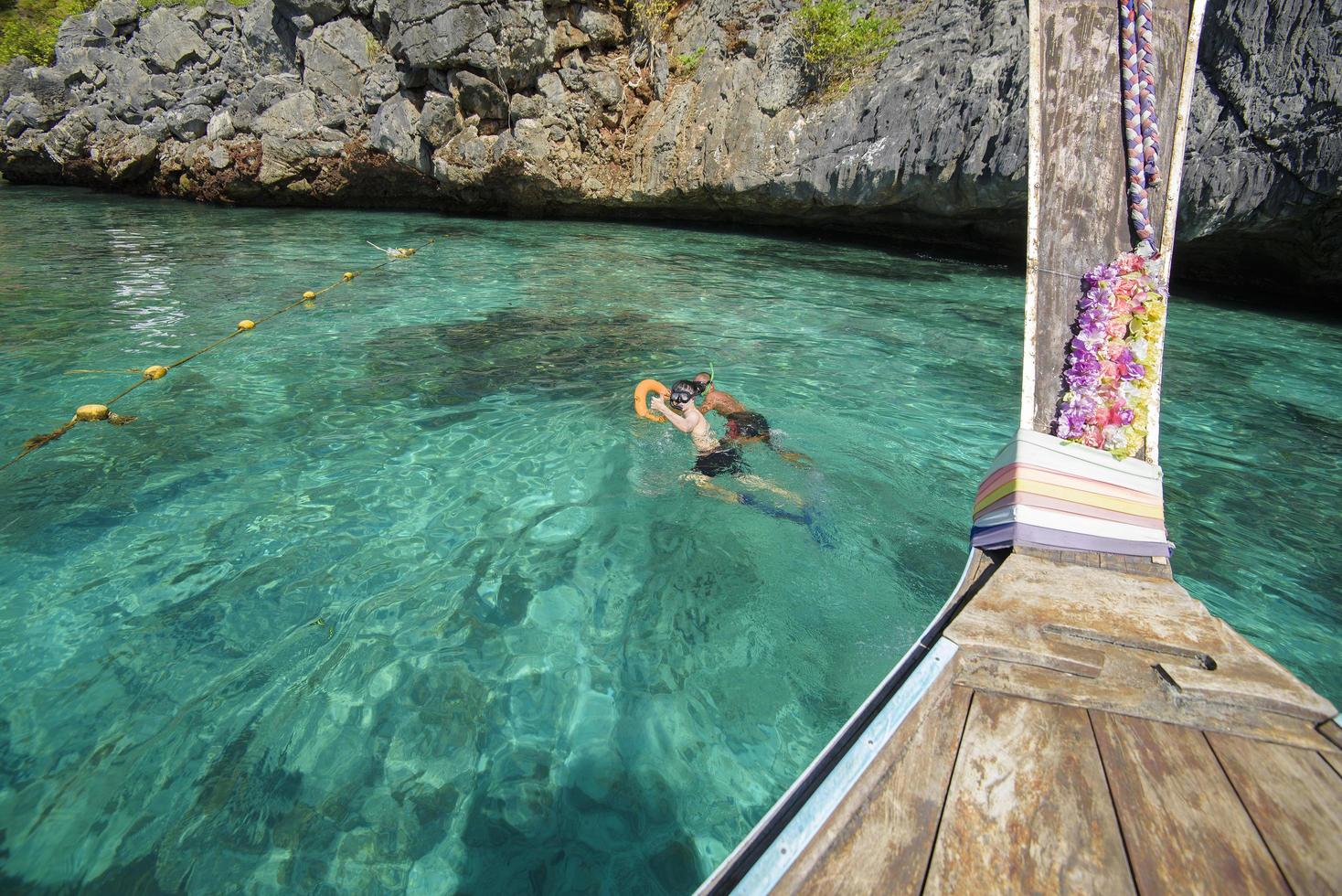 view from thai traditional longtail Boat while tourists snorkeling and diving in the ocean, Phi phi Islands, Thailand photo