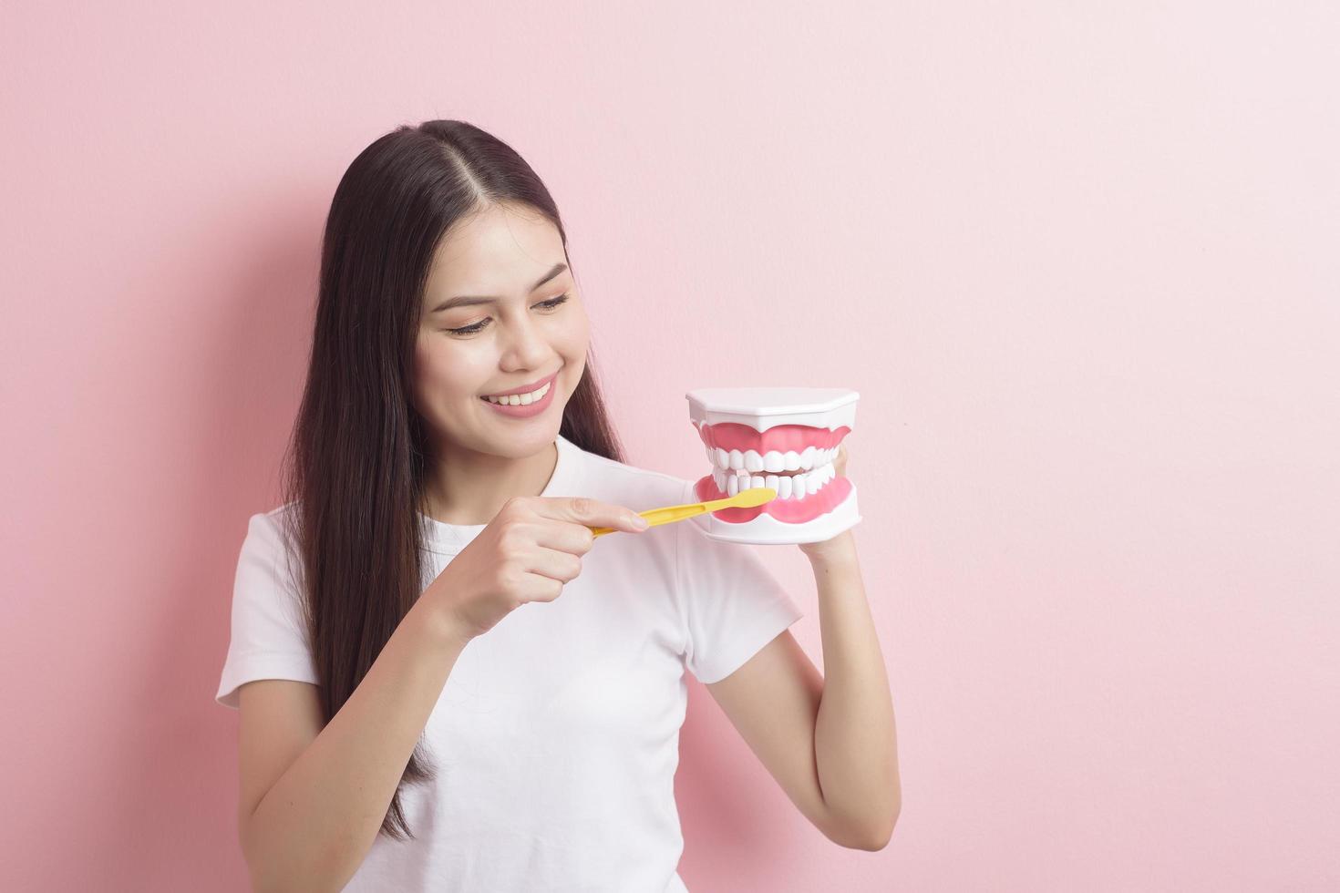 hermosa mujer sostiene dientes modelo artificial para demostración limpieza dental foto