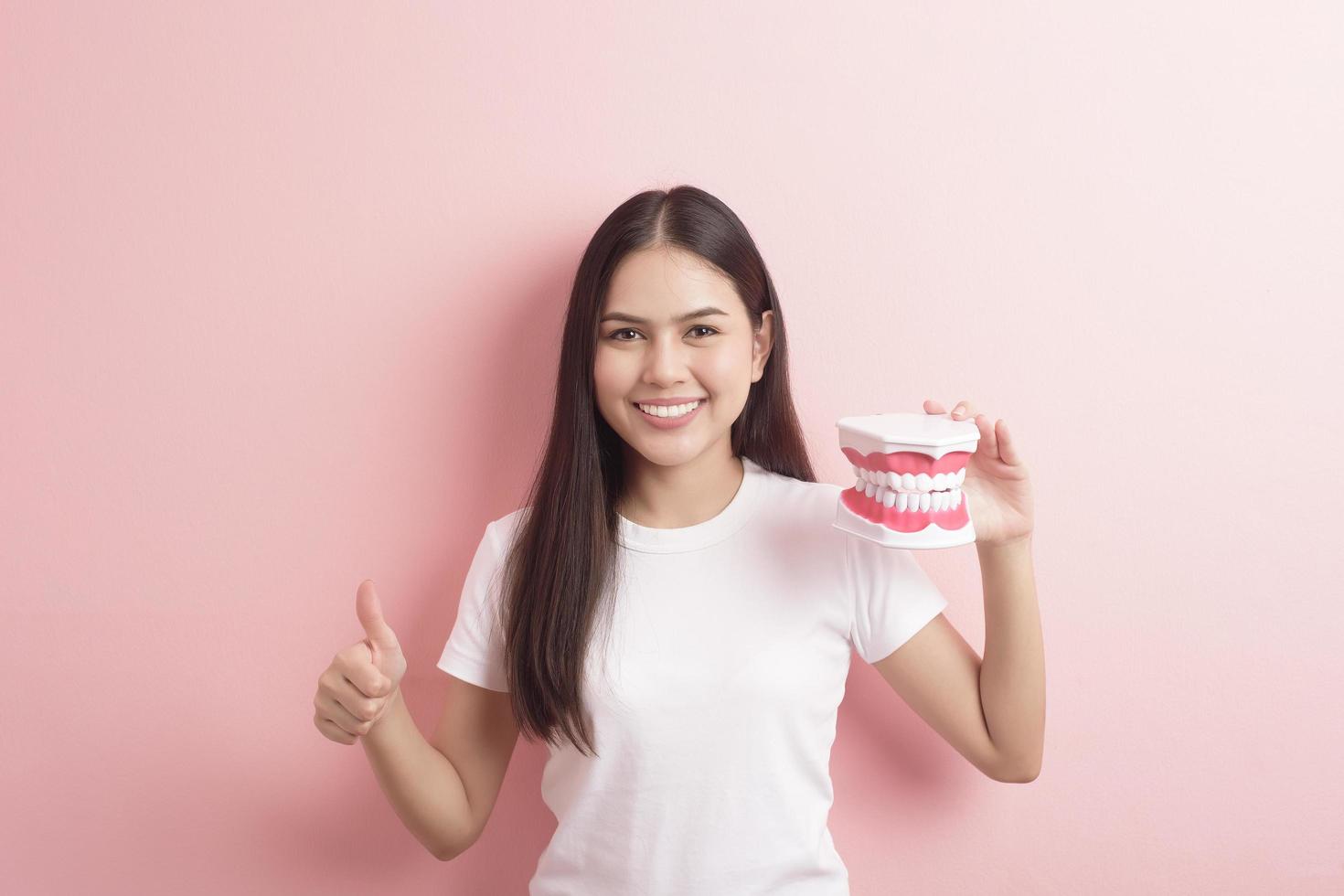 hermosa mujer sostiene dientes modelo artificial para demostración limpieza dental foto