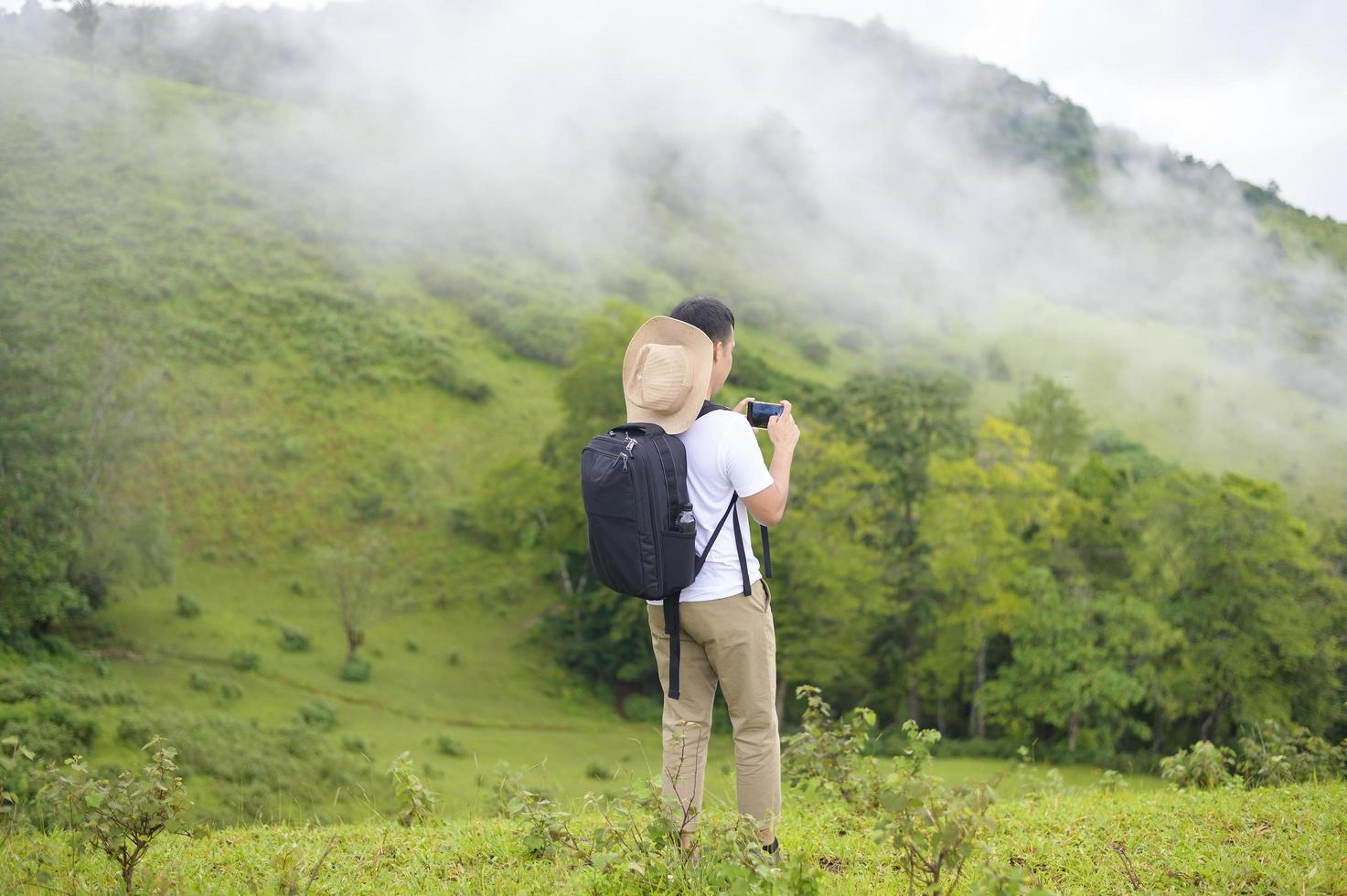 Traveling man enjoying and relaxing over beautiful green mountain view in rain season, Tropical climate. photo
