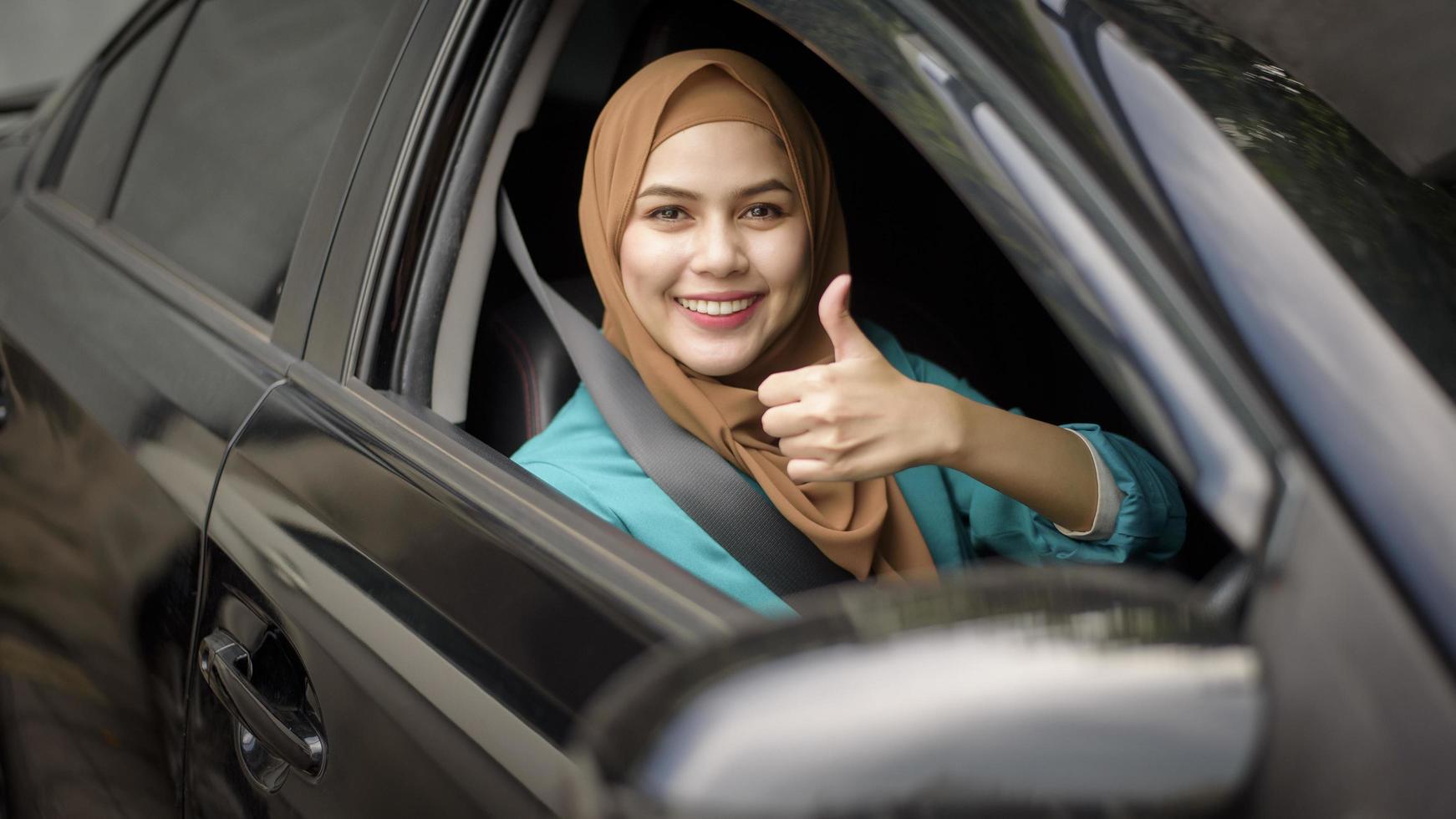 hermosa mujer de negocios con hiyab está sonriendo en su auto foto