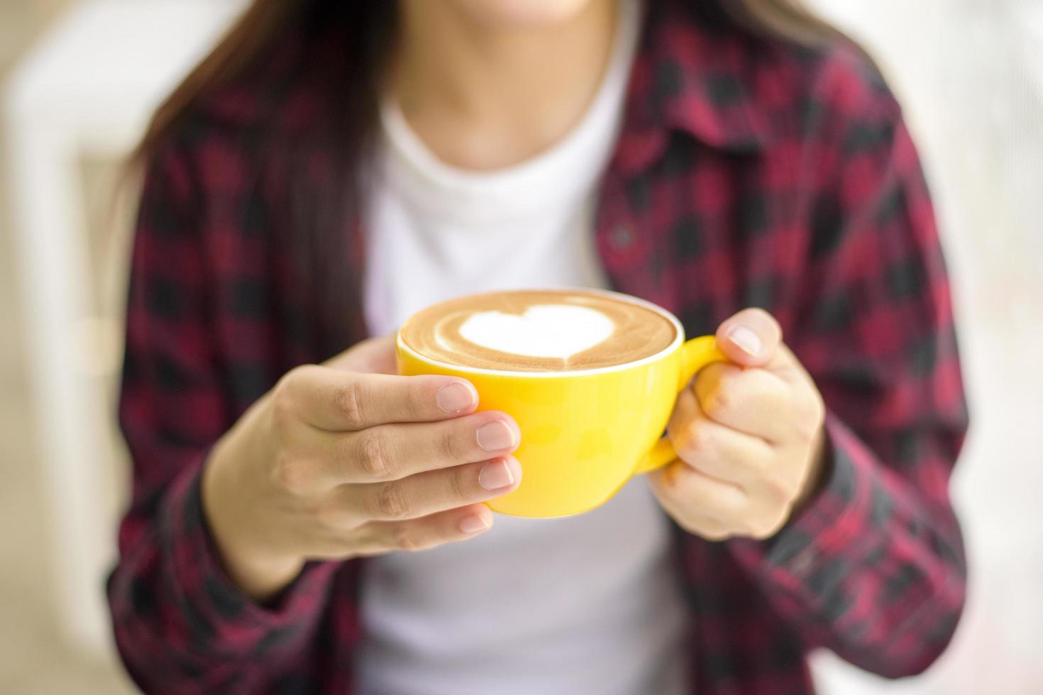 arte latte caliente en taza amarilla en el escritorio de trabajo foto