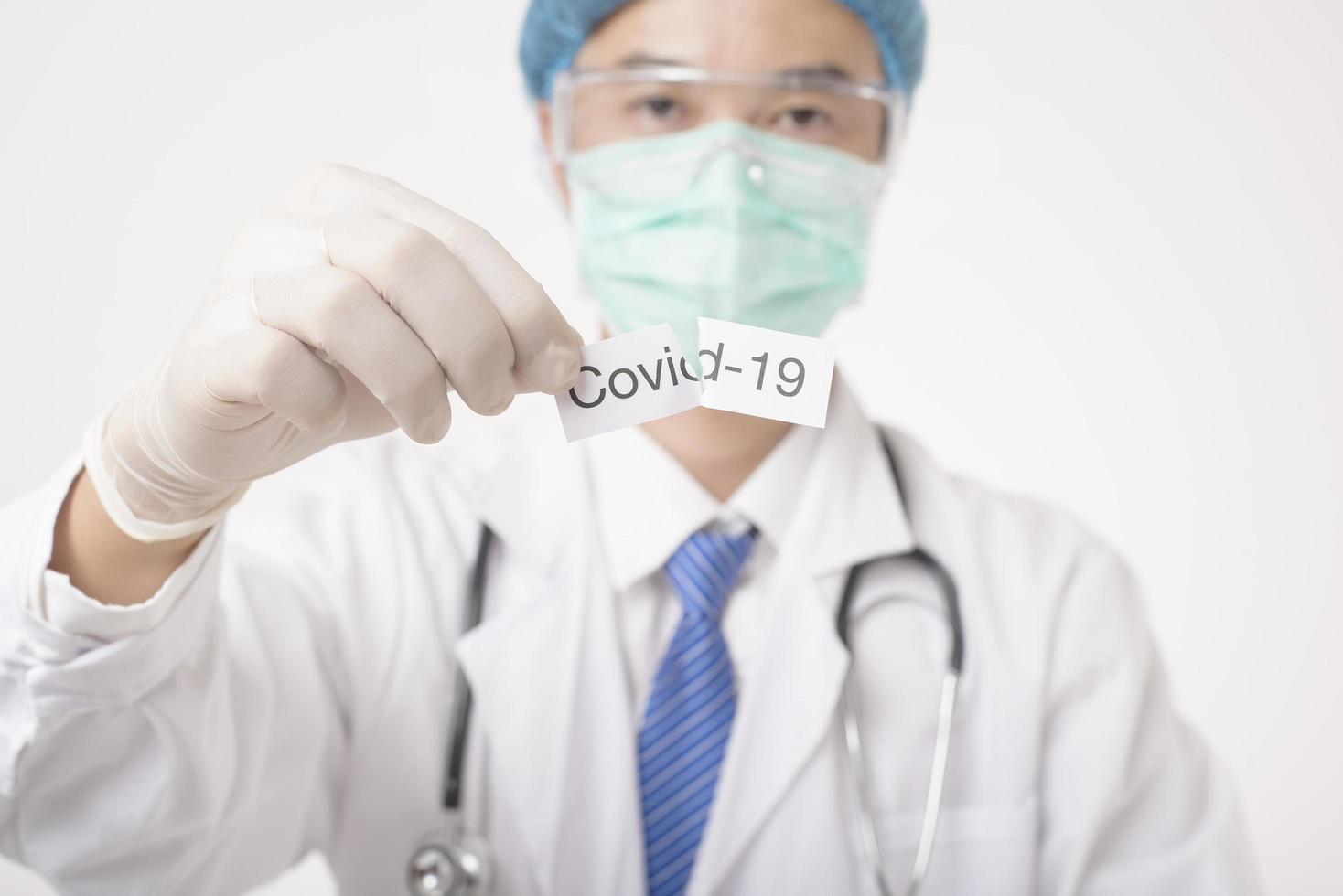Doctor is holding Covid-19 card on white background photo