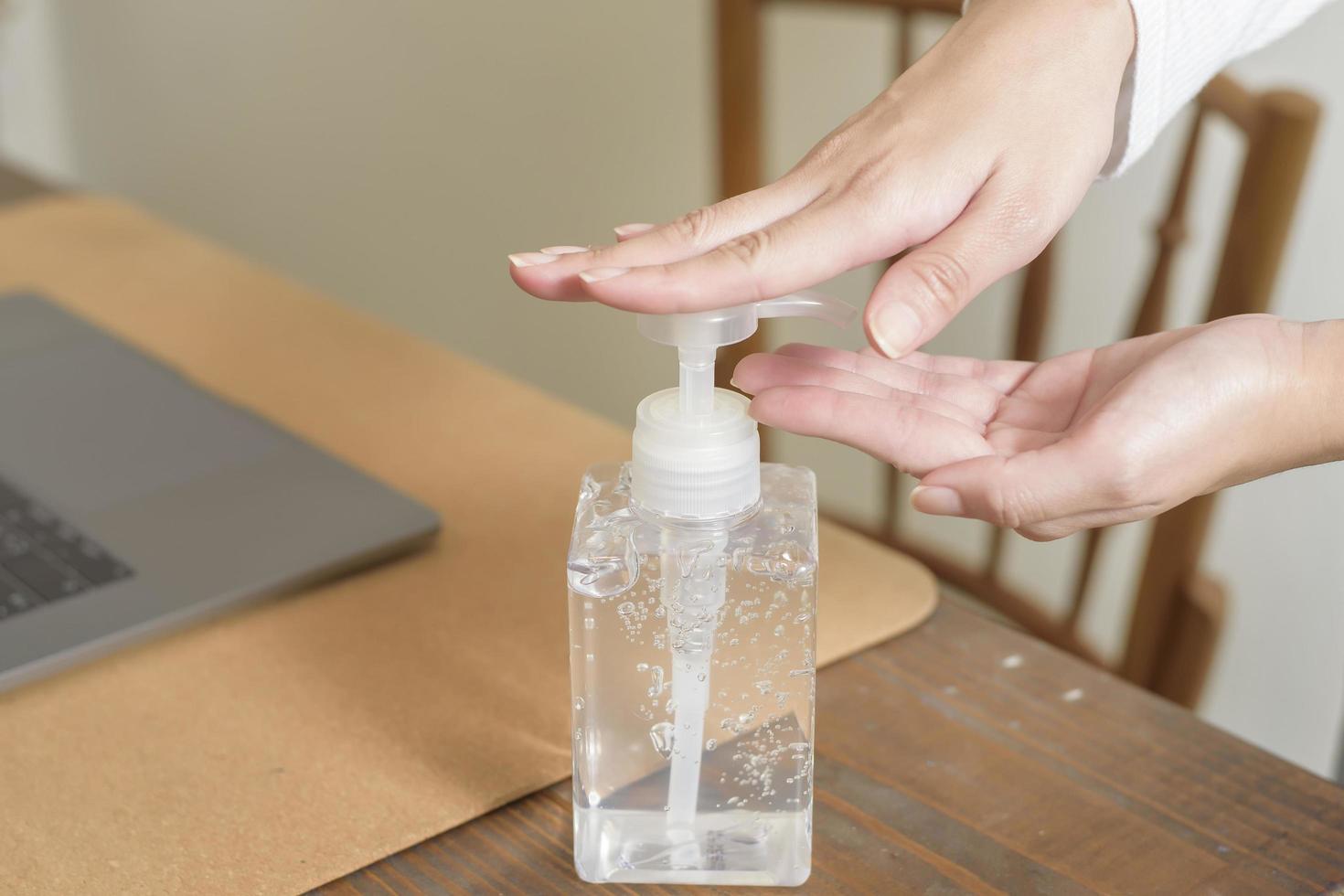 la mujer está aplicando gel desinfectante en las manos en el escritorio de trabajo foto