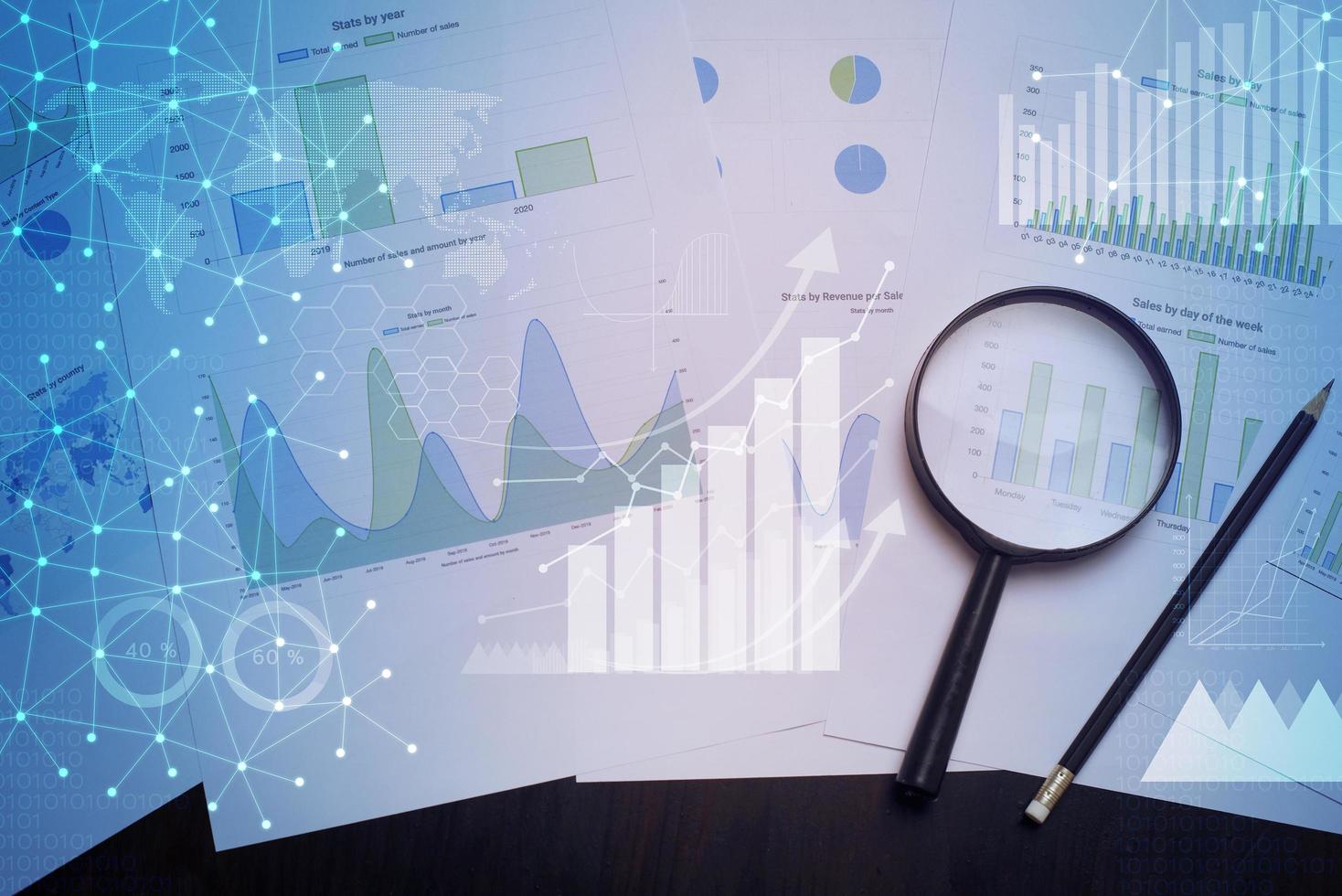 Magnifying glass and documents with analytics data lying on table photo