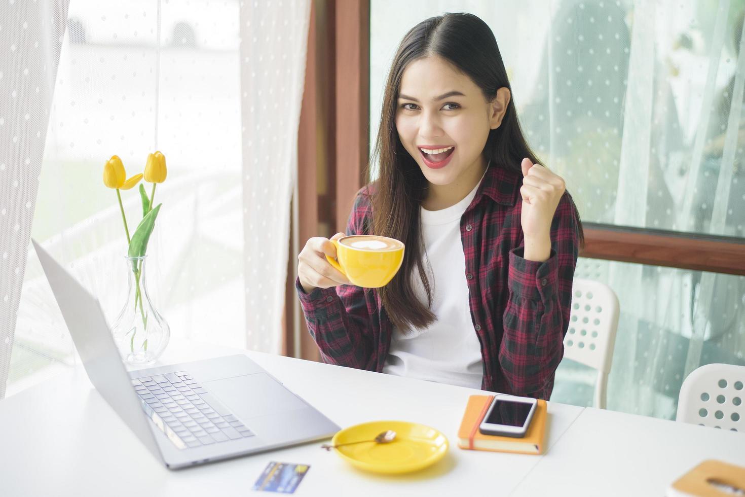 bella mujer está trabajando con una computadora portátil en una cafetería foto