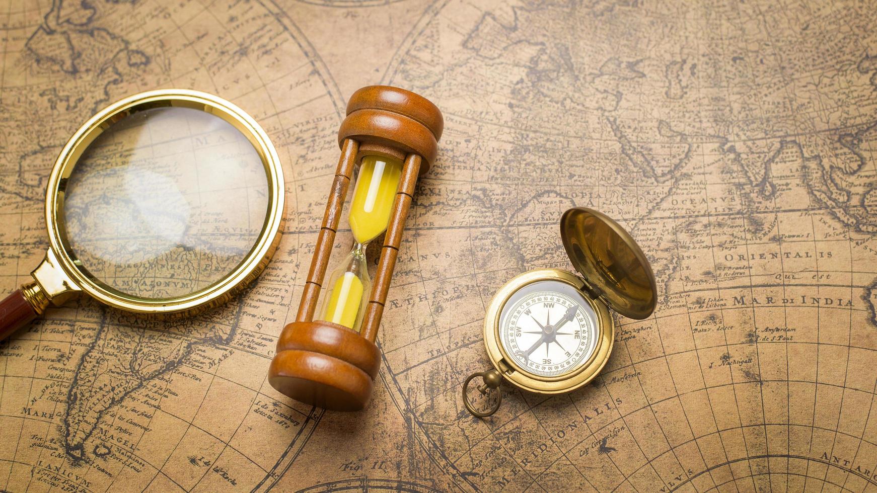 Old compass , magnifying glass and sand clock  on vintage map photo