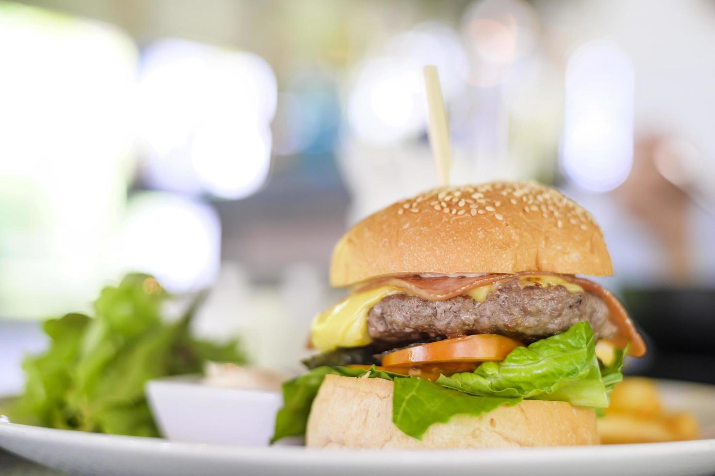Large of tasty burger with beef, tomato, cheese and lettuce served in a plate photo
