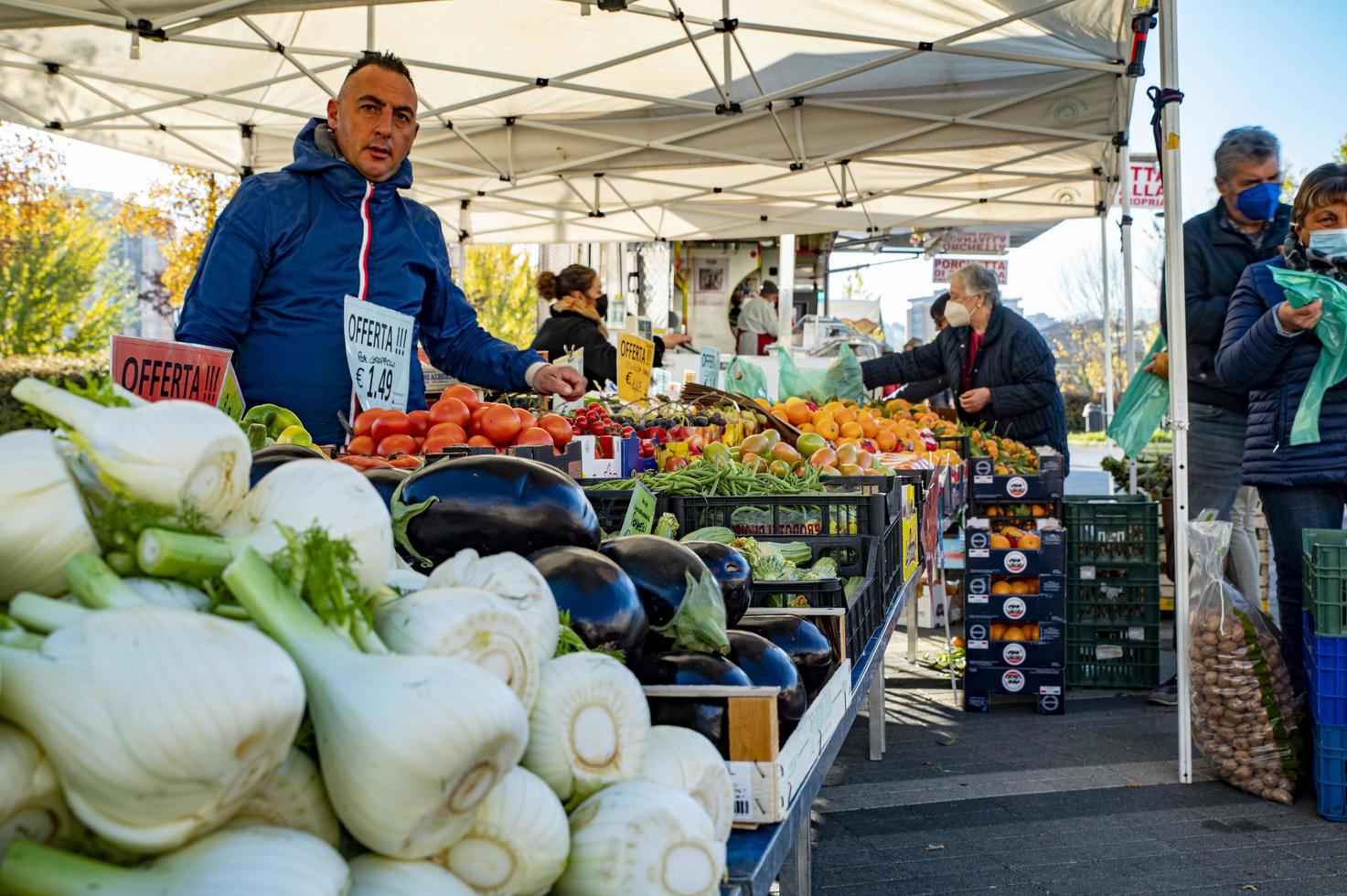 puesto de frutas y verduras con vendedores y clientes foto