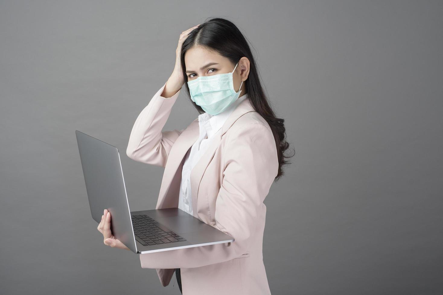 mujer de negocios con mascarilla quirúrgica tiene computadora portátil foto