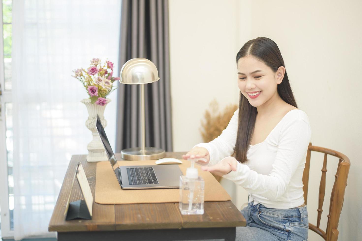 Woman is applying sanitizer gel to hands on working desk photo