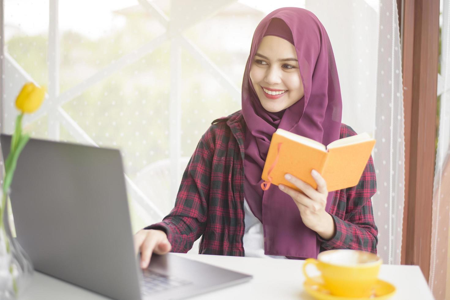 Muslim woman with hijab is working with laptop computer in coffee shop photo