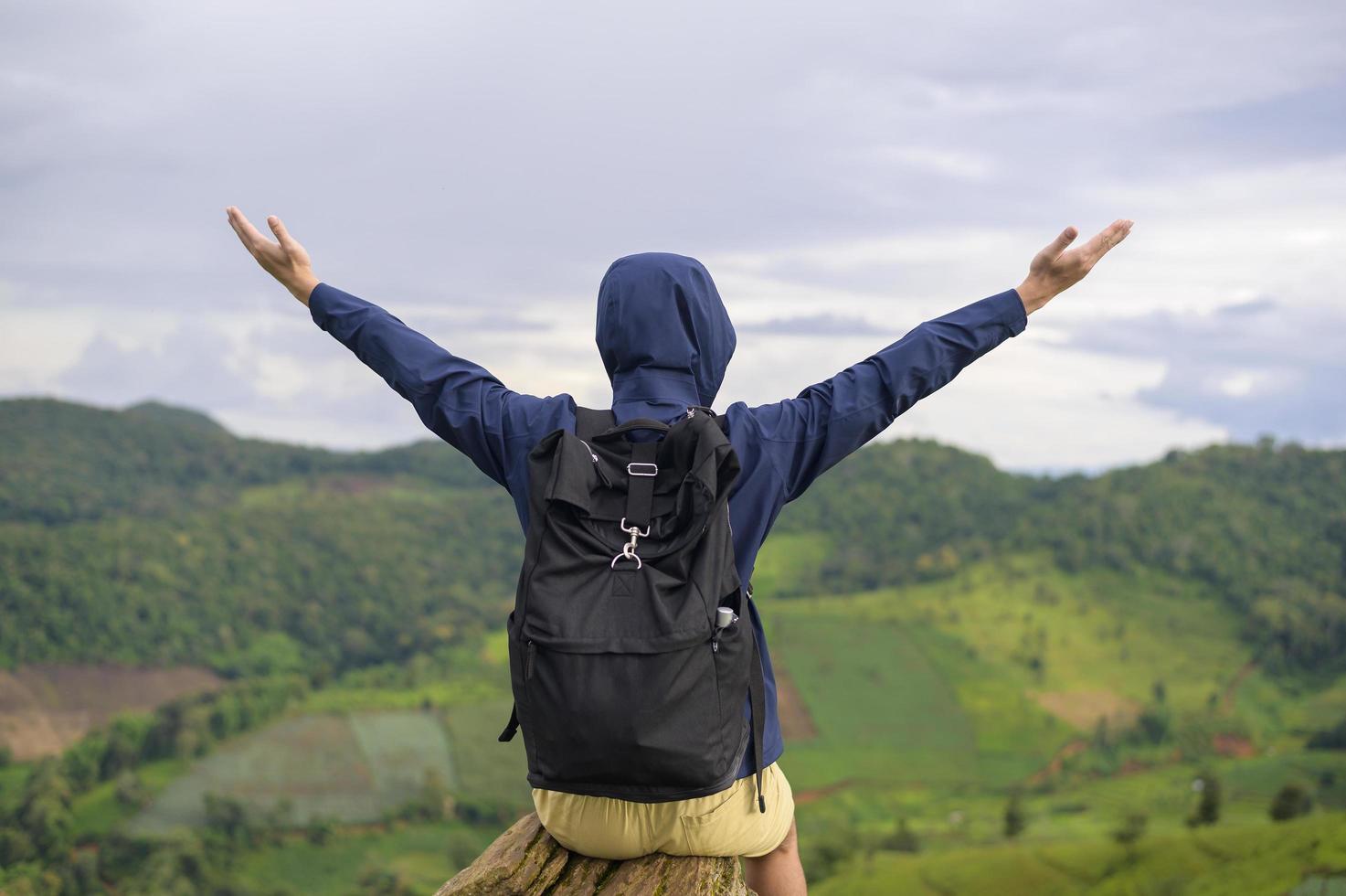 hombre viajero disfrutando y relajándose sobre la hermosa vista verde de la montaña en temporada de lluvia, clima tropical. foto