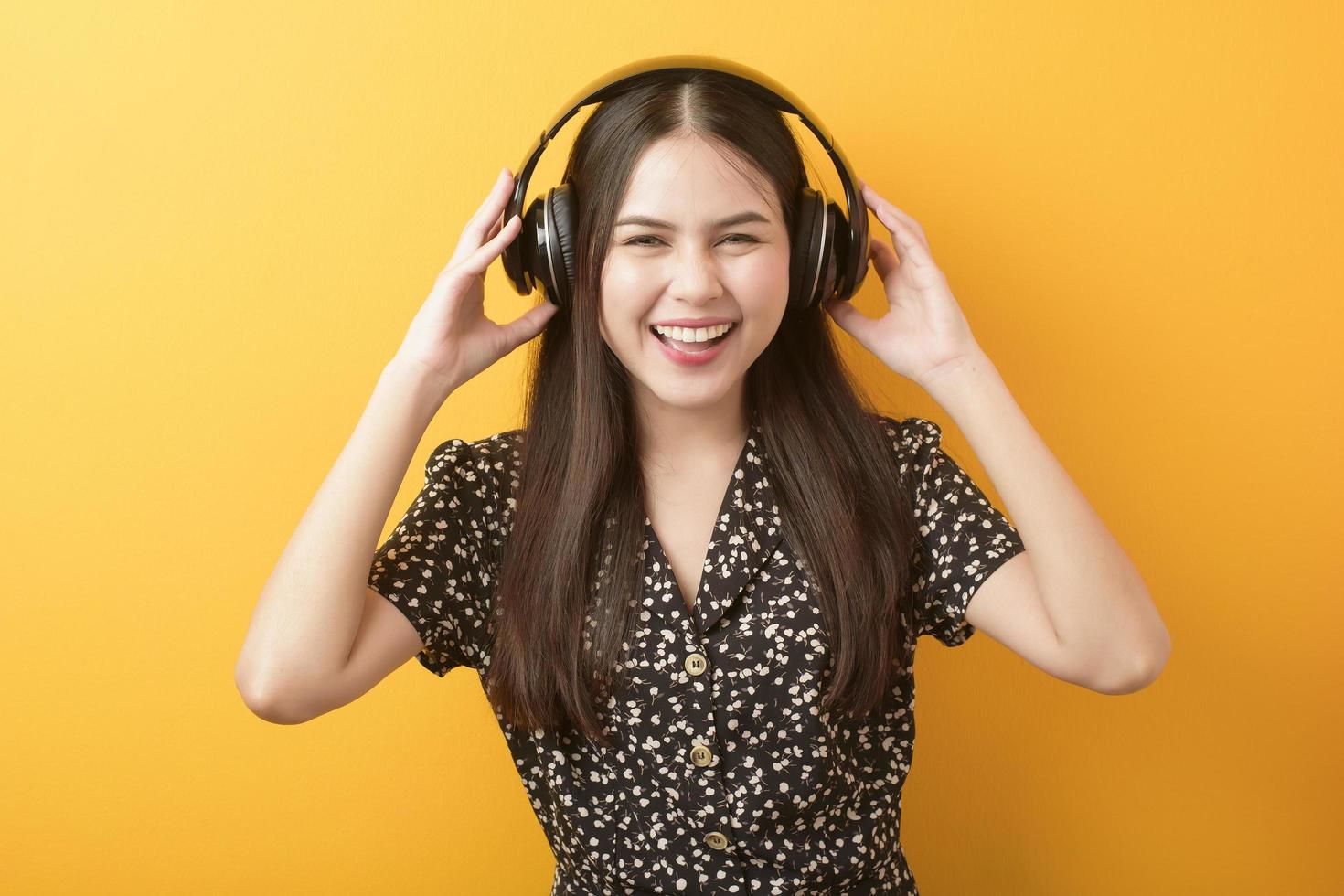 Music lover woman is enjoying with headset on yellow background photo