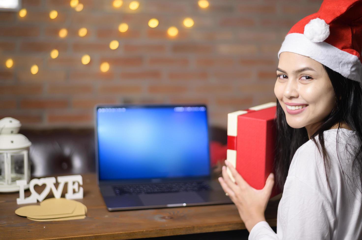 joven mujer sonriente con sombrero rojo de santa claus haciendo videollamadas en las redes sociales con familiares y amigos el día de navidad. foto