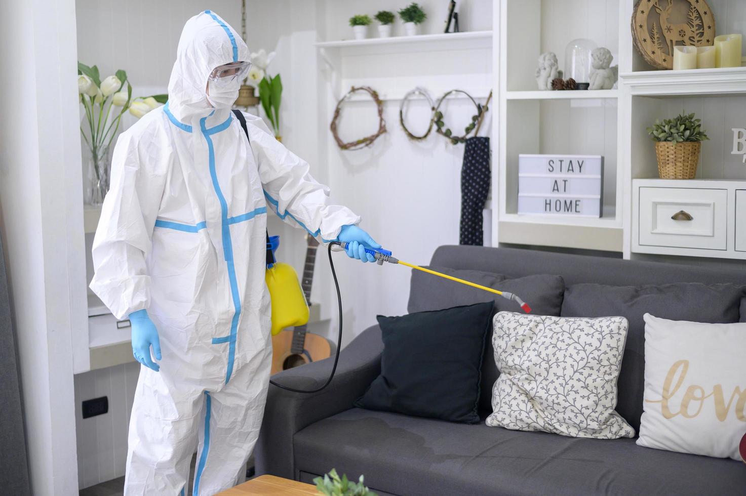 un personal médico con traje de ppe está usando spray desinfectante en la sala de estar, protección covid-19, concepto de desinfección. foto