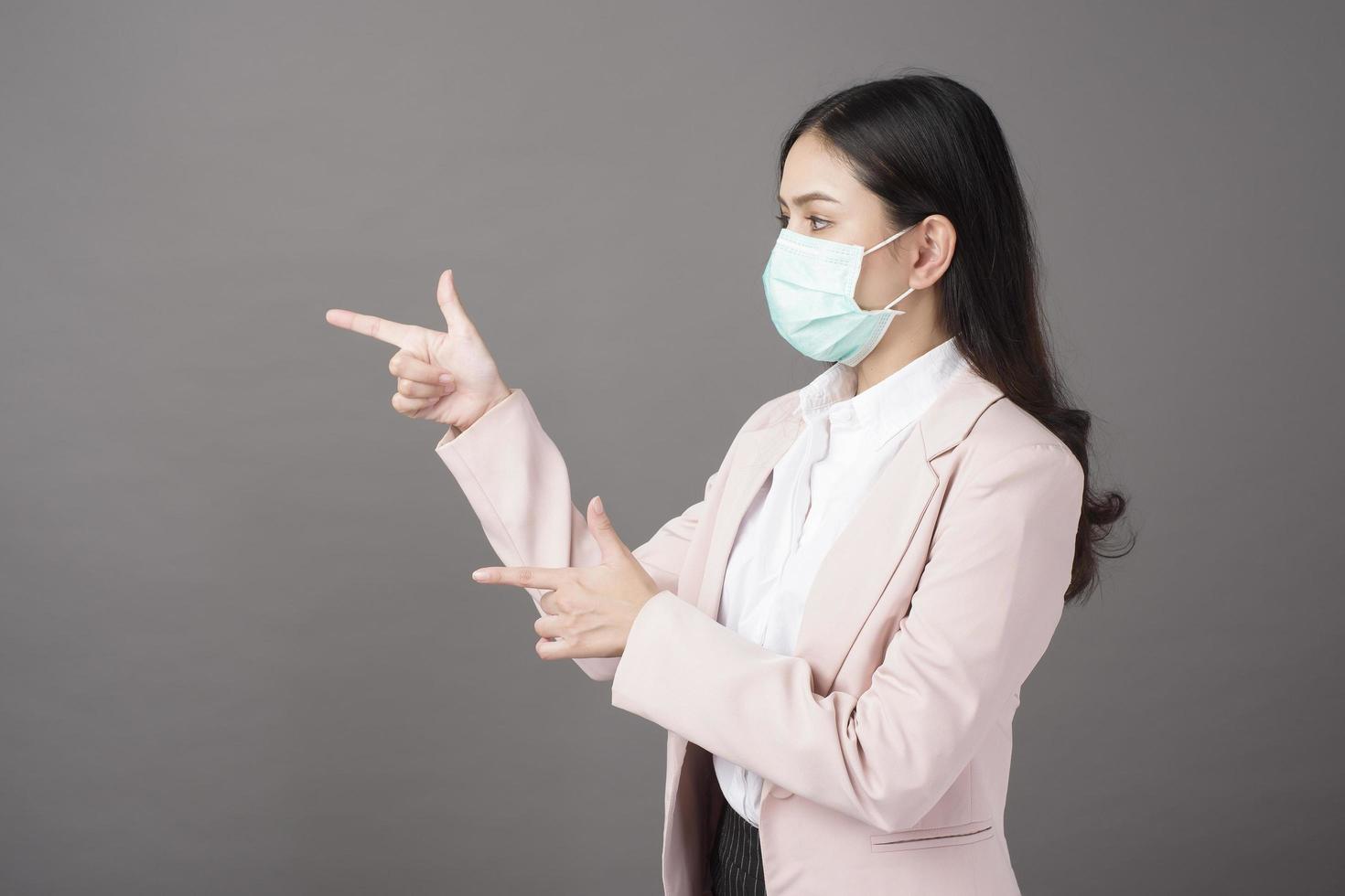 Business woman with mask  is showing something on her hand photo