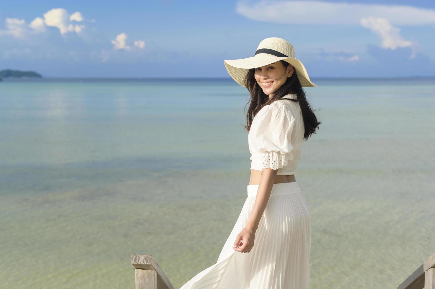 una hermosa mujer feliz con vestido blanco disfrutando y relajándose en el concepto de playa, verano y vacaciones foto