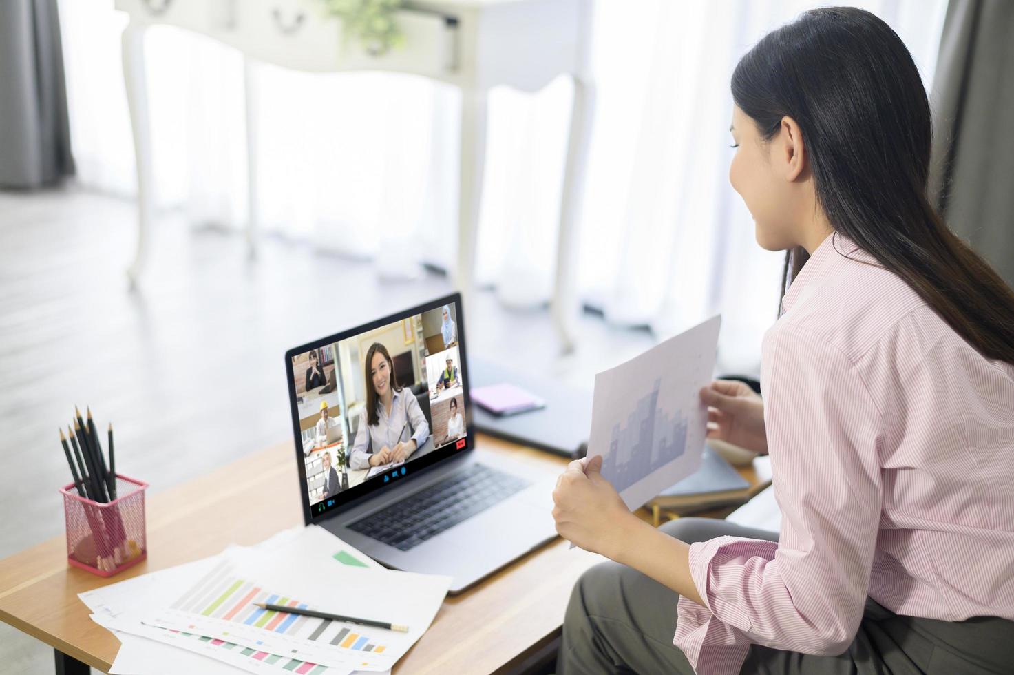 una joven está trabajando con la pantalla de su computadora mientras se reúne a través de una aplicación de videoconferencia. foto