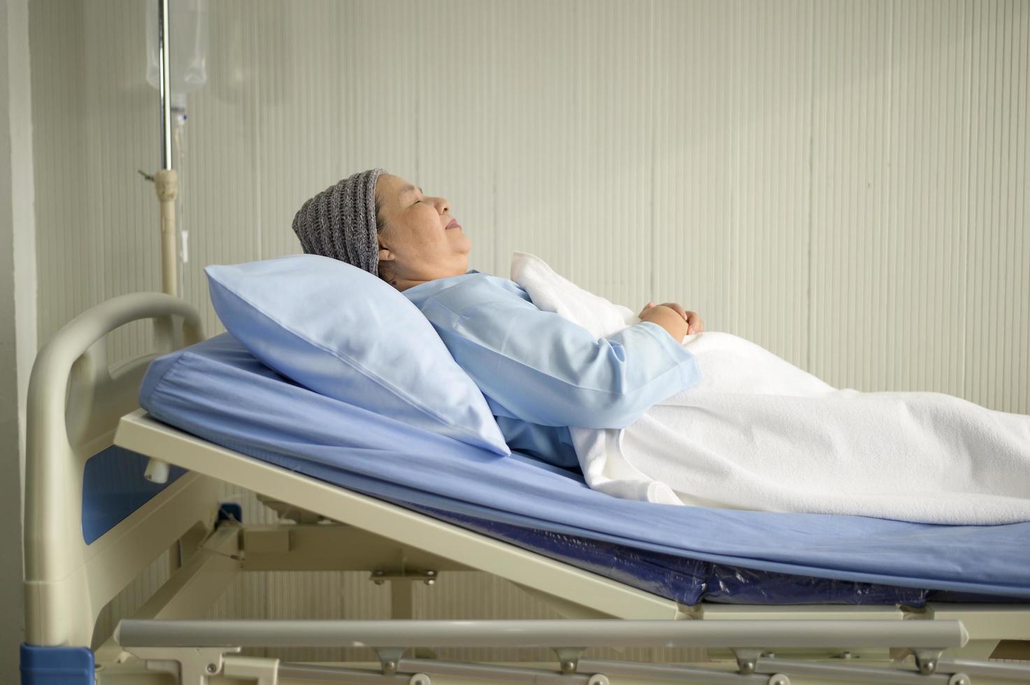Depressed and hopeless Asian cancer patient woman wearing head scarf in hospital. photo